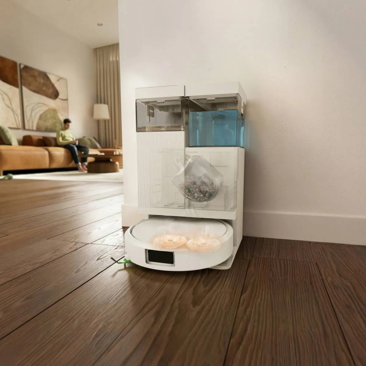 Biały robot sprzątający ze stacją ładującą przechowującą brud i wodę. W tle salon.