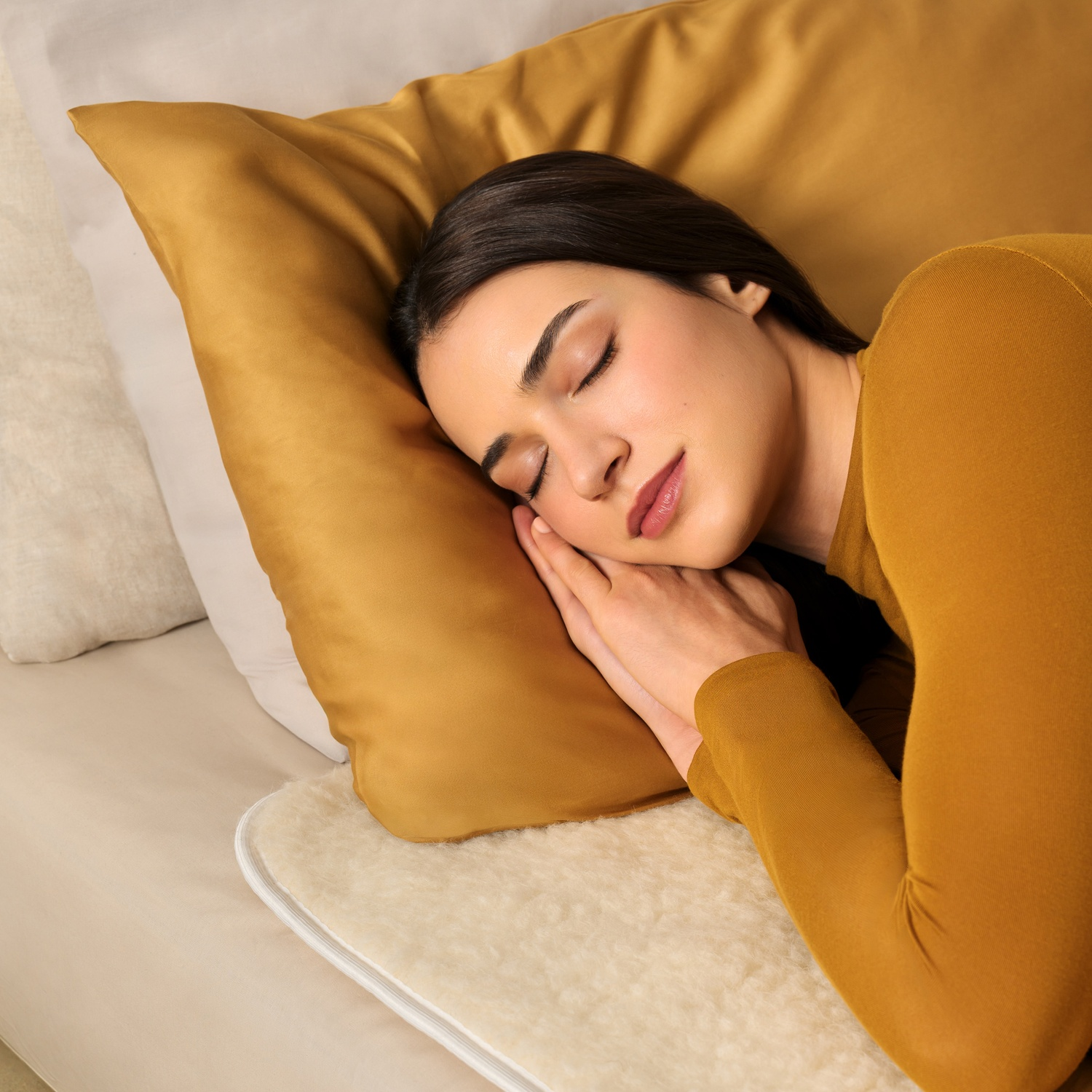Una donna dorme su un cuscino con una pelle di pecora sotto.