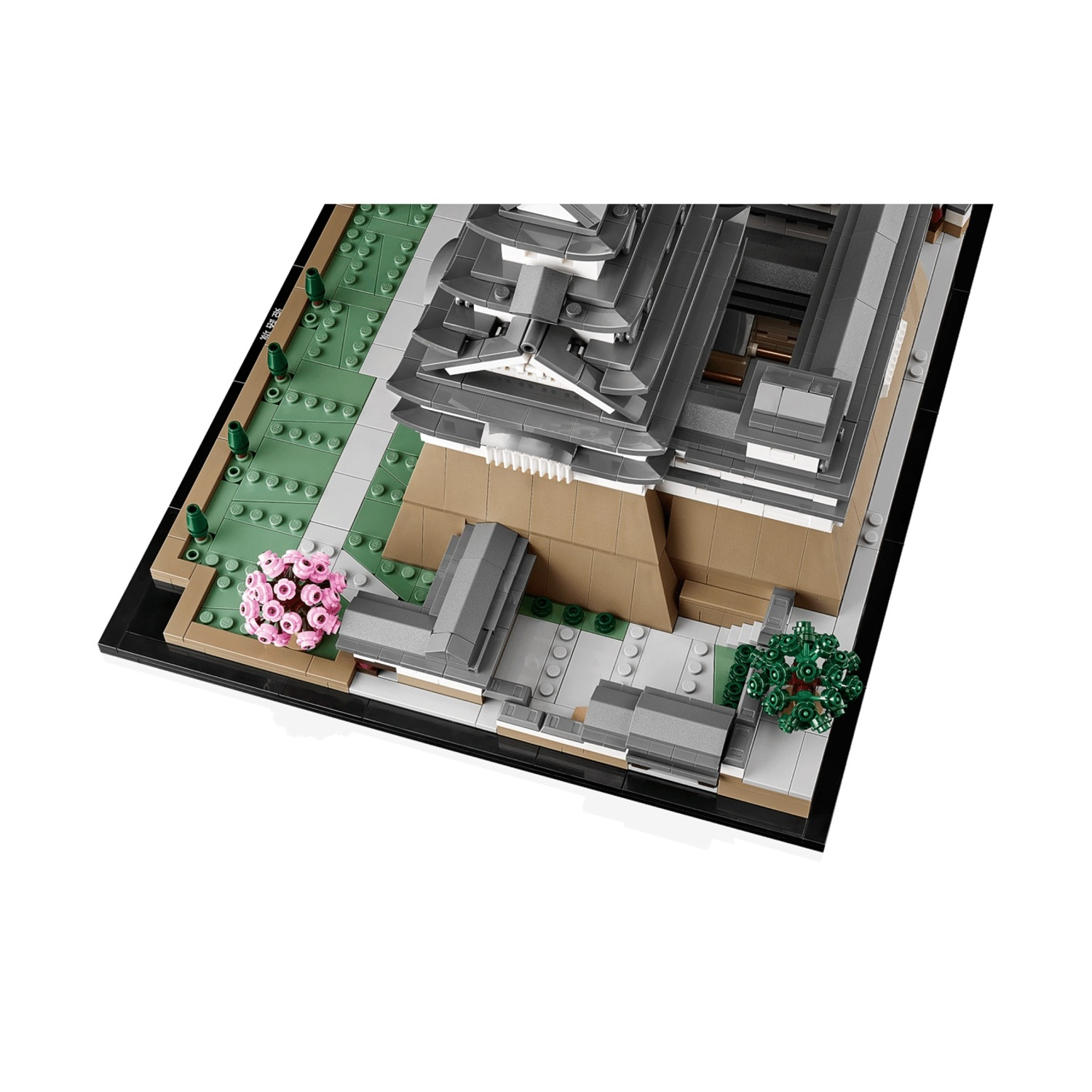 Un modello di castello Lego grigio con alberi verdi e fiori rosa.