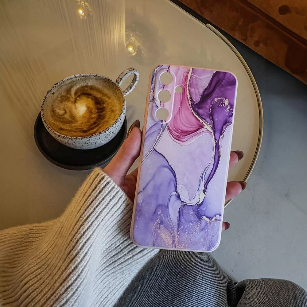 Egy kéz kávéscsésze mellett tart egy márványos telefontokot.