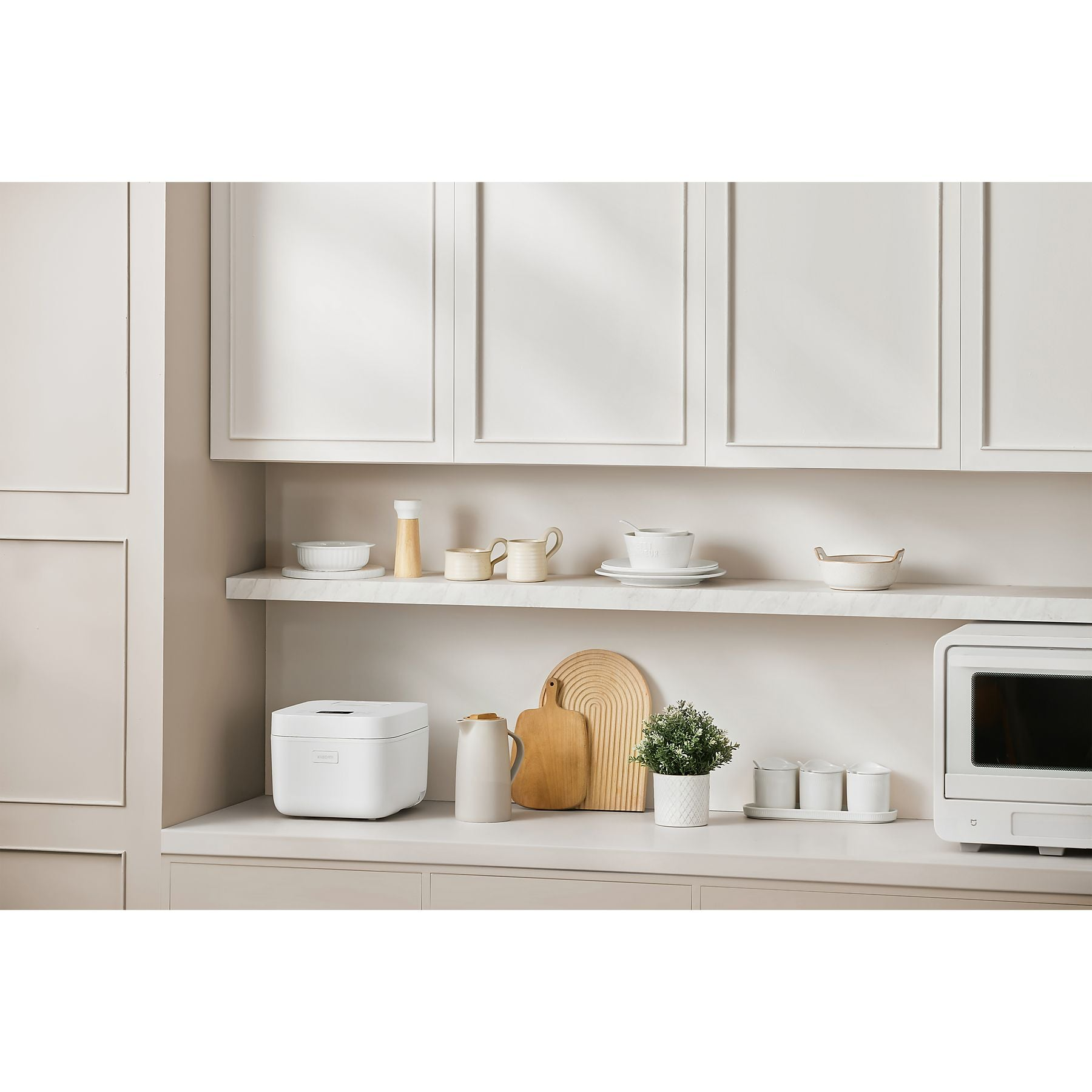 Cocina blanca con electrodomésticos y platos en estantes.