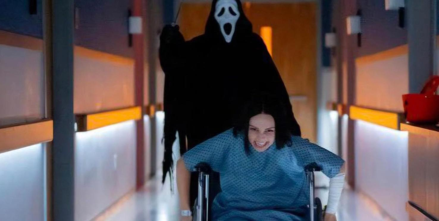 Eine Person im Rollstuhl wird von Ghostface in einem Krankenhausflur gejagt.