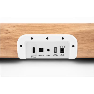 Panel de conexión con HDMI, Óptico, Aux, USB y entrada CC sobre superficie de madera.