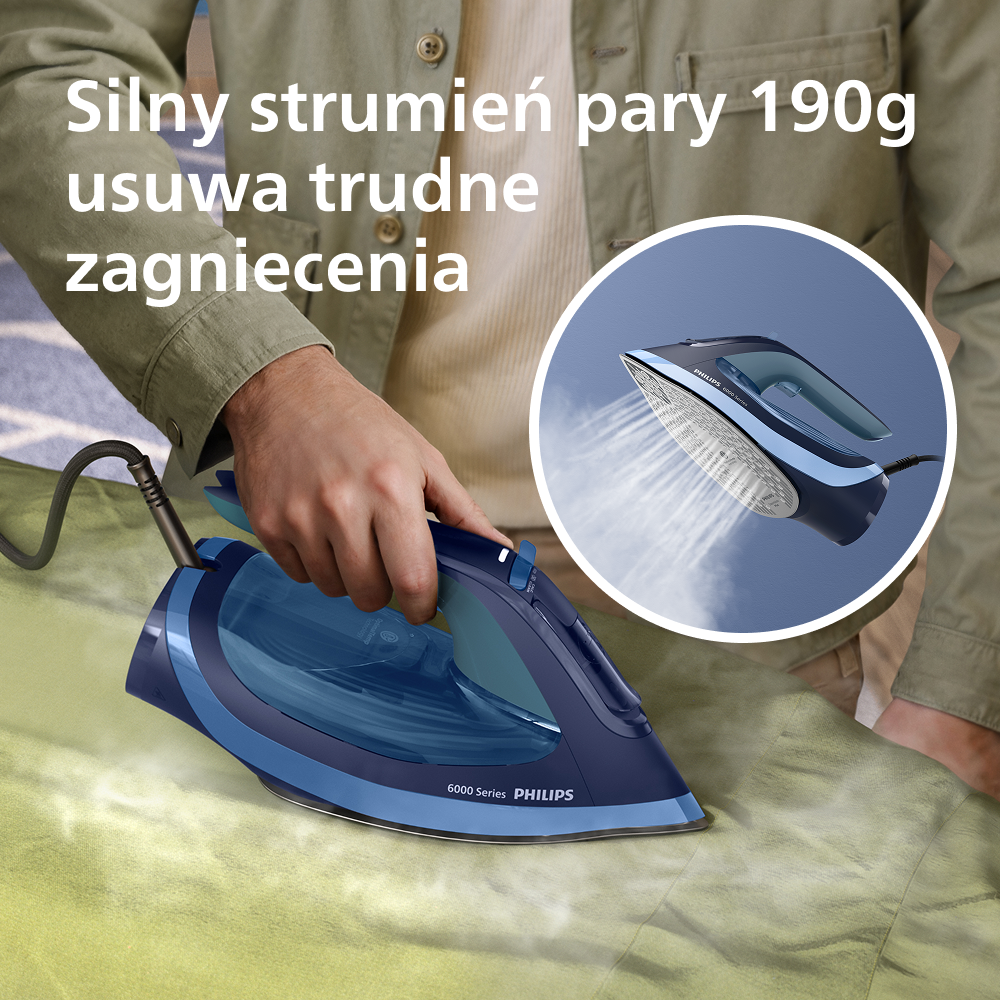 Dłoń trzyma niebieskie żelazko, spryskując parą zieloną tkaninę. Zbliżenie.