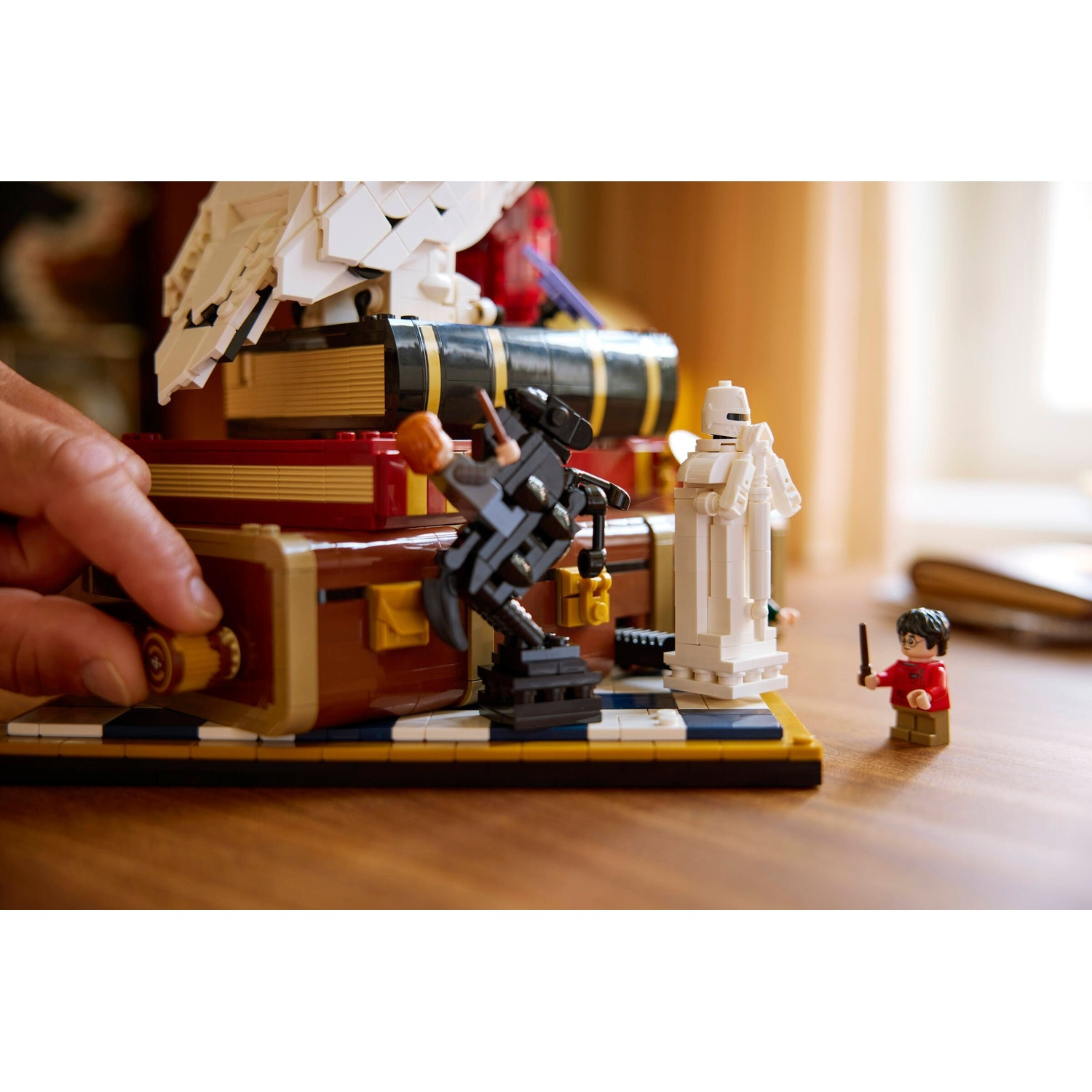 Un uomo sta costruendo un set Lego con Harry Potter, un gufo e un robot bianco da scacchi.
