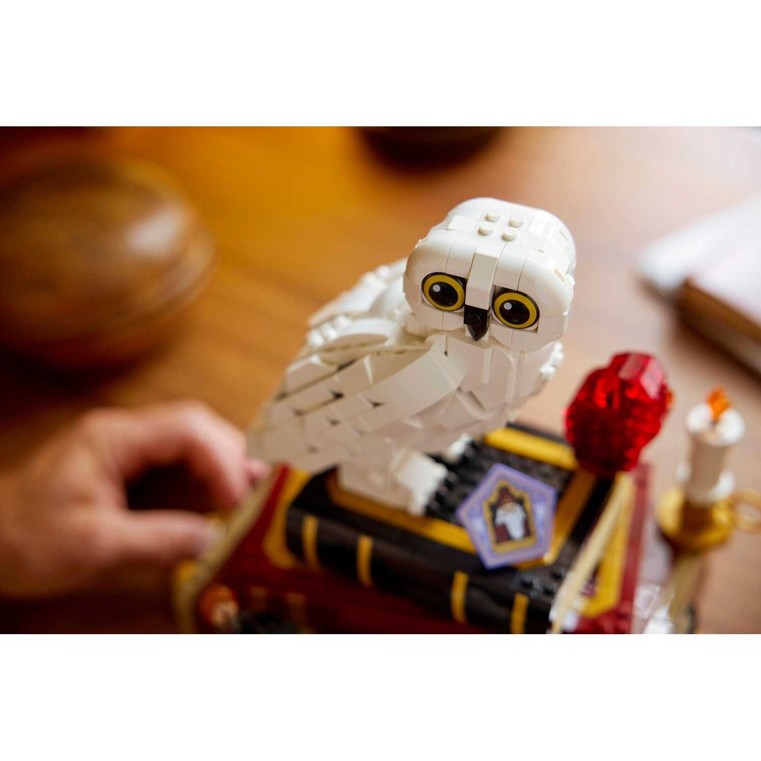 Una costruzione di gufo delle nevi bianco Lego siede su un libro con un distintivo da mago.
