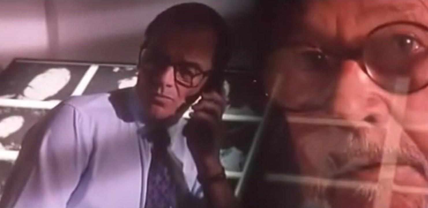 Mann mit Brille telefoniert, Röntgenbilder im Hintergrund.