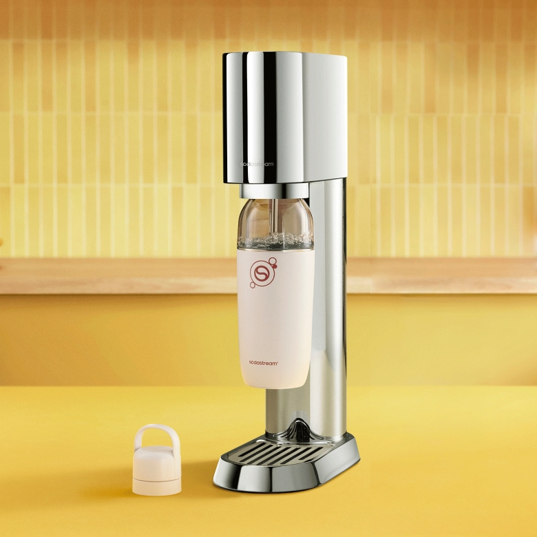 Srebrny SodaStream z jasno różową butelką na żółtym tle.
