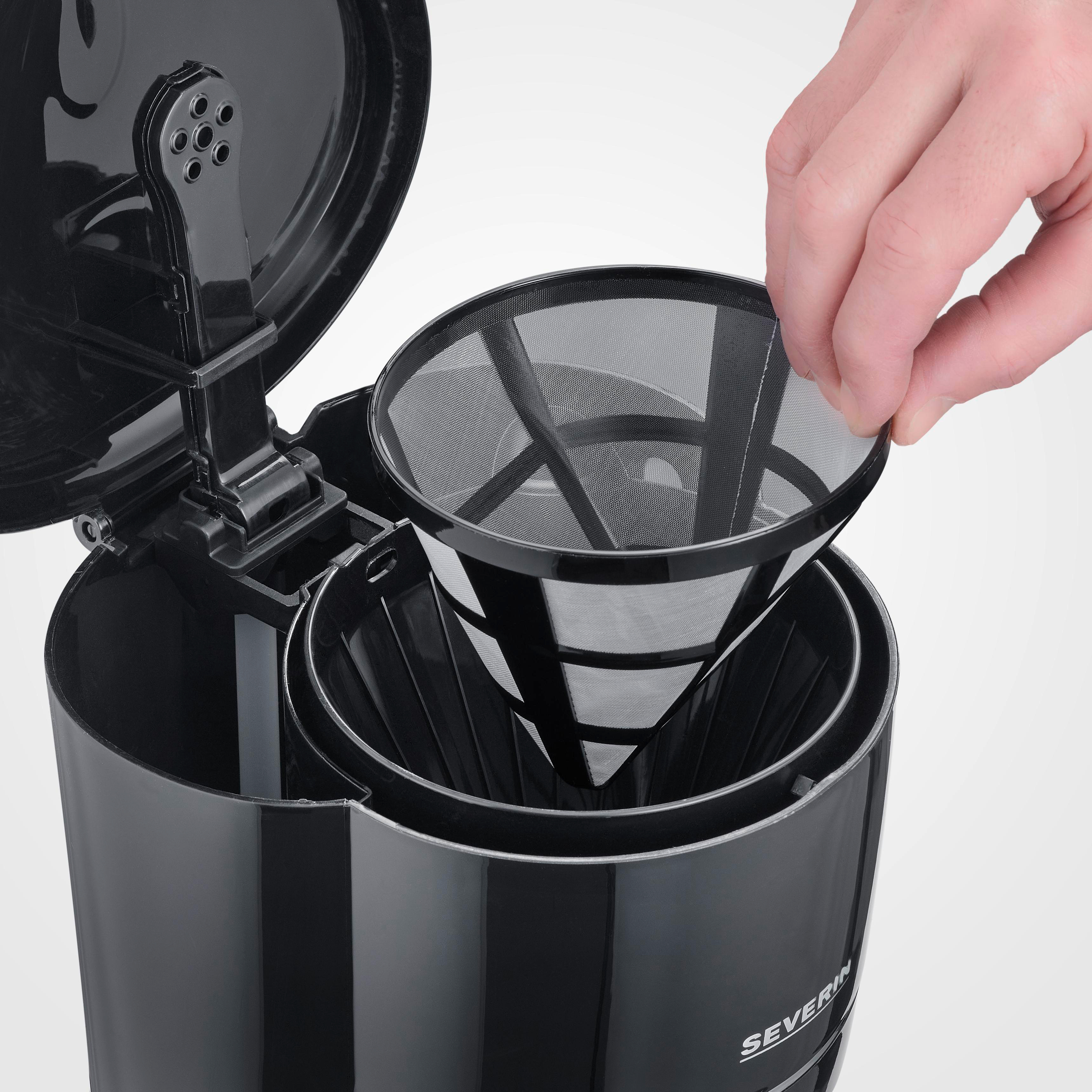 Eine Hand setzt einen schwarzen Kaffeefilter in eine Kaffeemaschine ein.