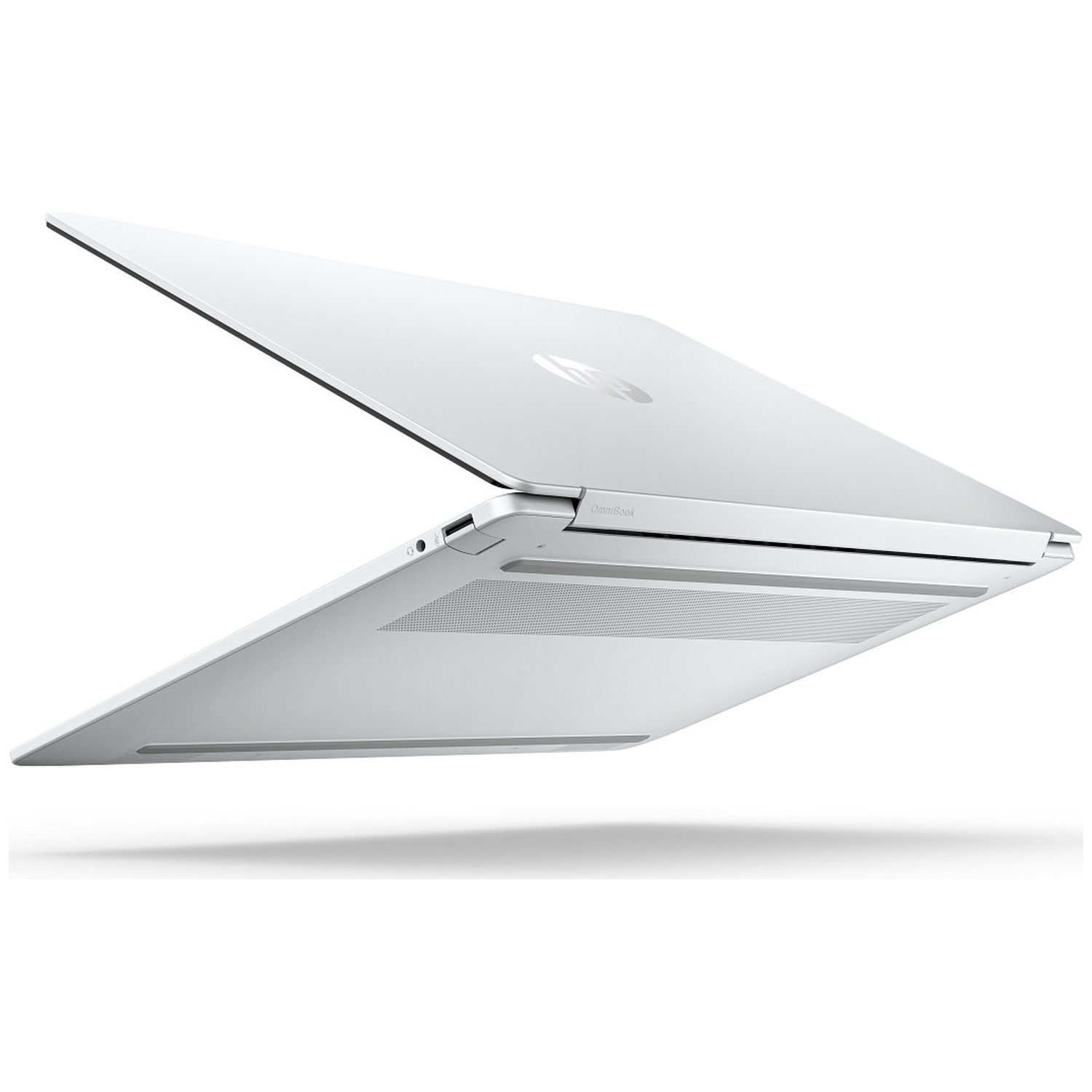 Un ordinateur portable blanc, vu par le dessous et légèrement de côté. Ouvert, montrant clavier et écran.