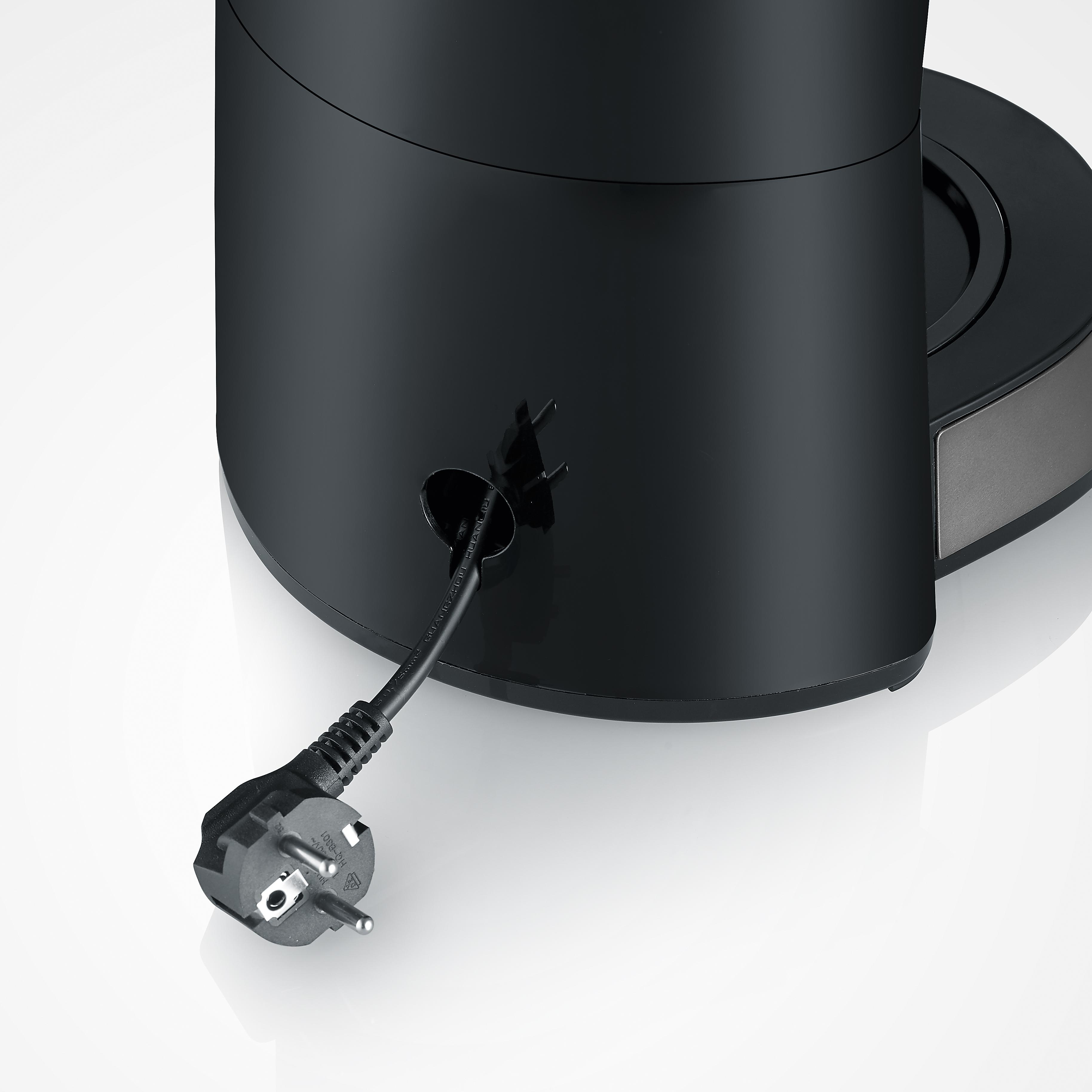 Ein schwarzes Stromkabel mit Stecker ragt aus einem schwarzen Gerät.