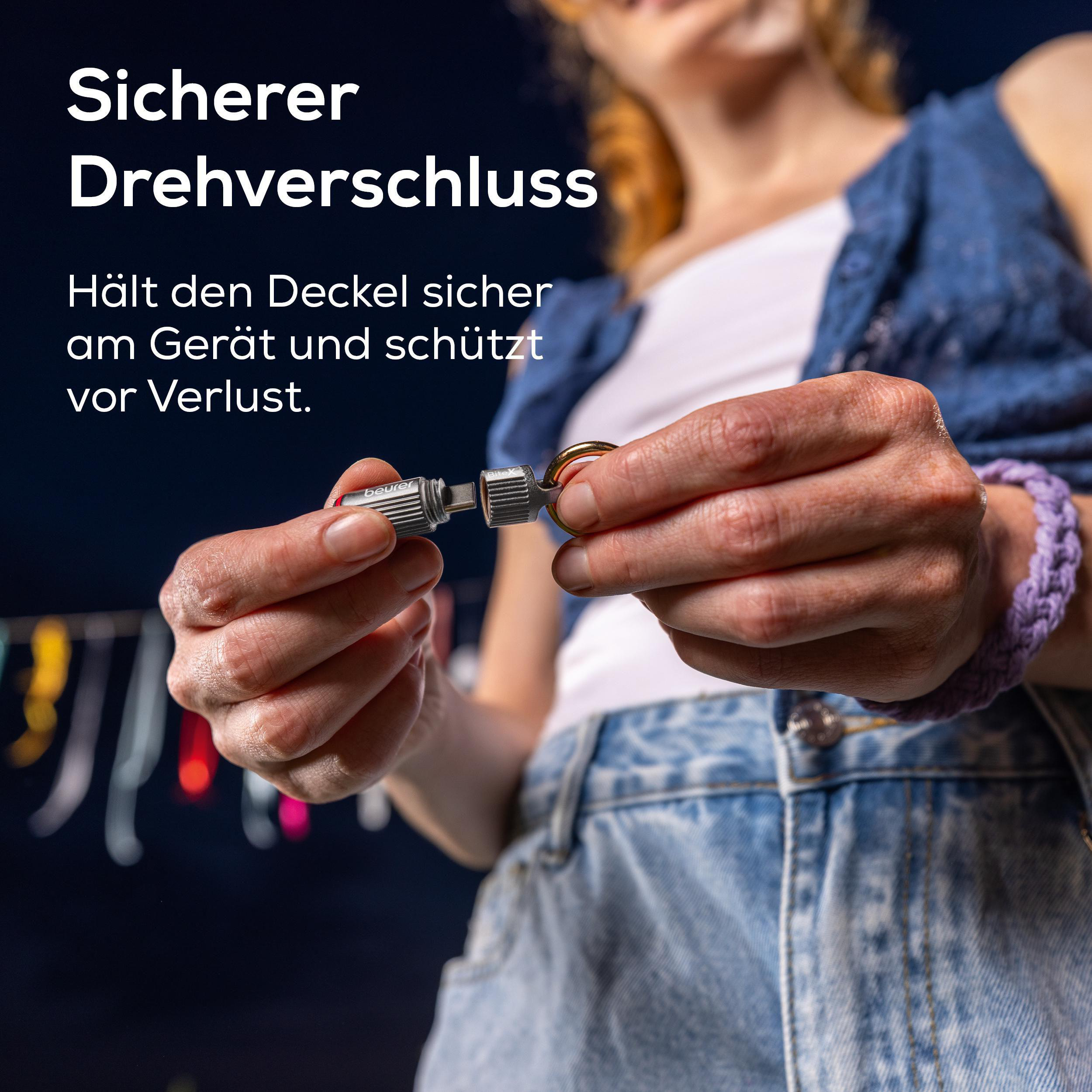 Hände halten einen silbernen Drehverschluss mit Ring.