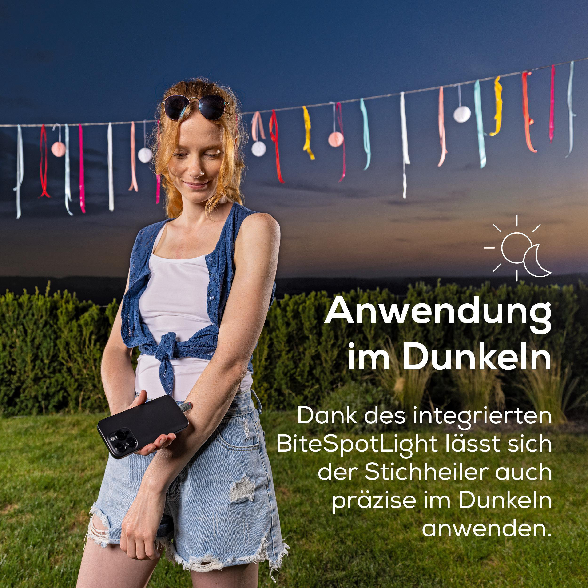 Frau mit roten Haaren hält Handy, bunten Bändern im Hintergrund.