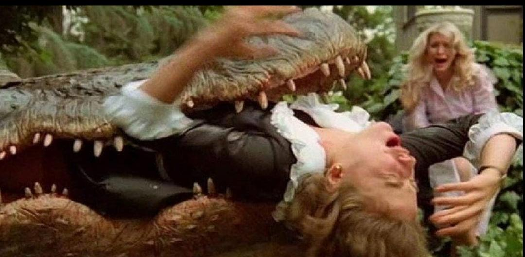 Eine Frau schreit vor Entsetzen, während ein Alligator ihr Gesicht packt.