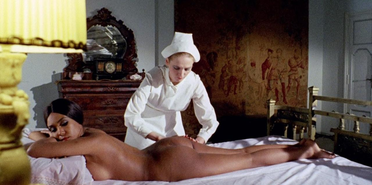 Eine Krankenschwester in weißer Uniform massiert die nackte Frau auf einem Bett.