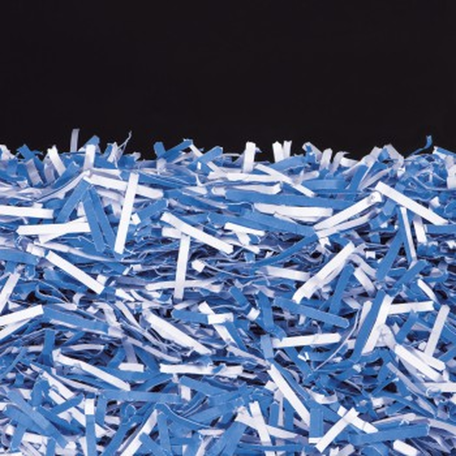 Stapel blauw en wit versnipperd papier tegen zwarte achtergrond.