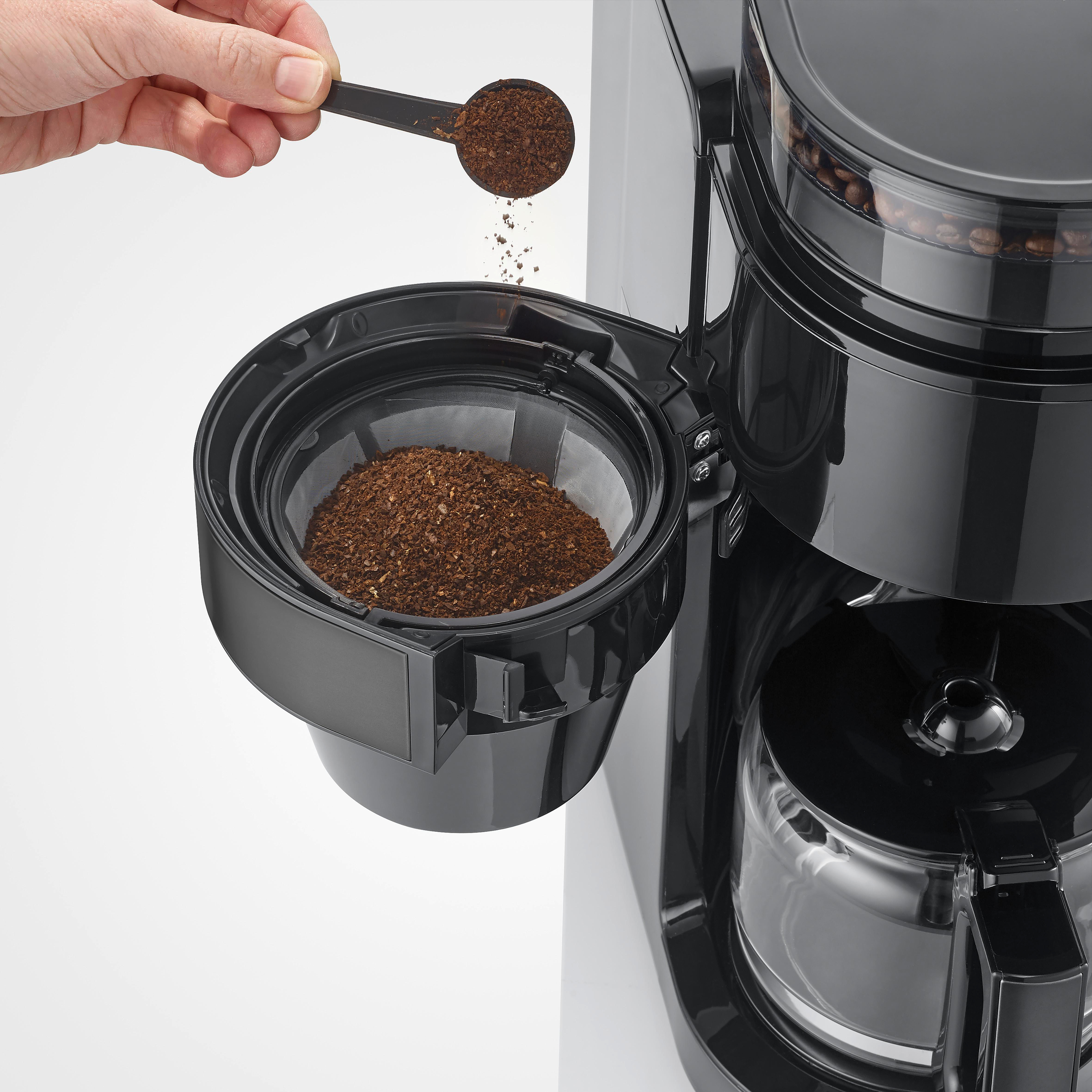 Eine Hand schüttet Kaffeepulver aus einem Löffel in einen Kaffeefilter.