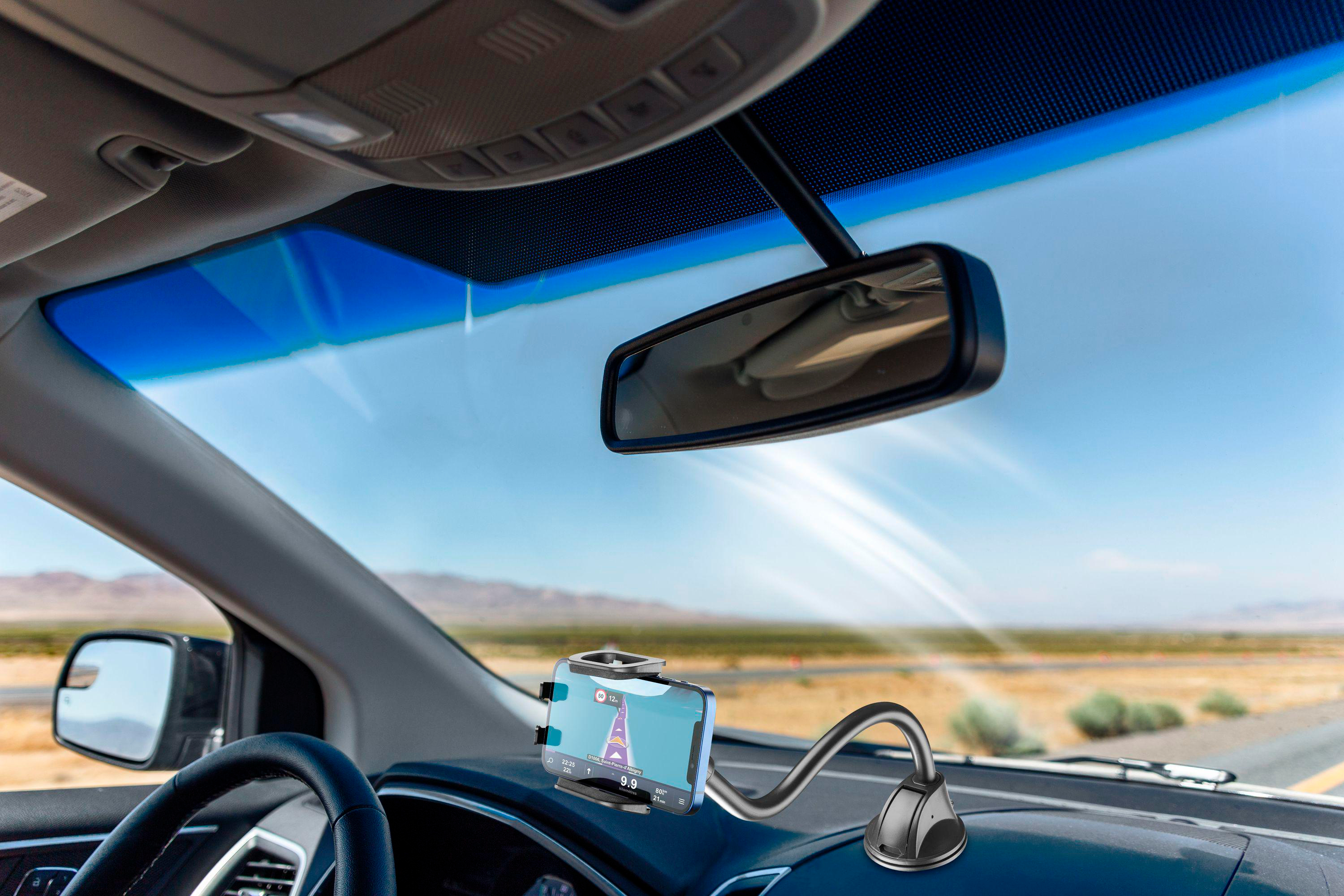 Handyhalterung am Armaturenbrett zeigt Navigations-App mit Straßen und Berge im Hintergrund.