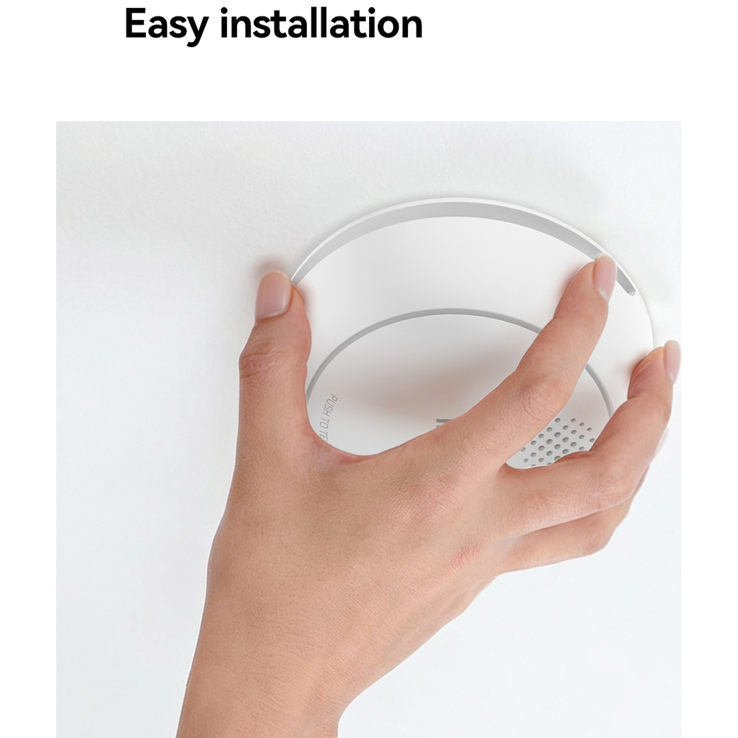 Een hand monteert een witte rookmelder aan een plafond.