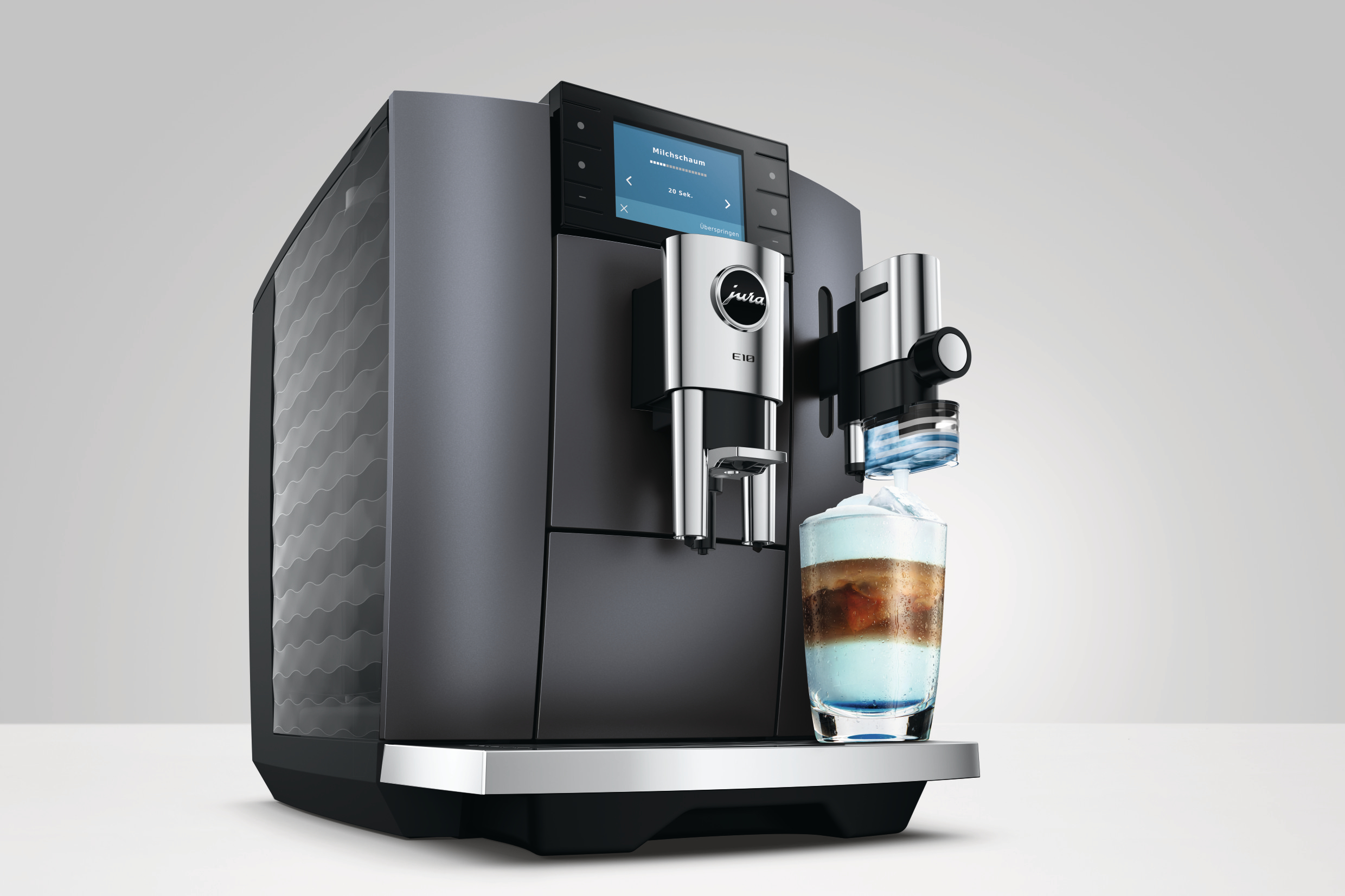 Eine moderne Kaffeemaschine brüht ein Getränk mit Milchschaum in ein Glas.