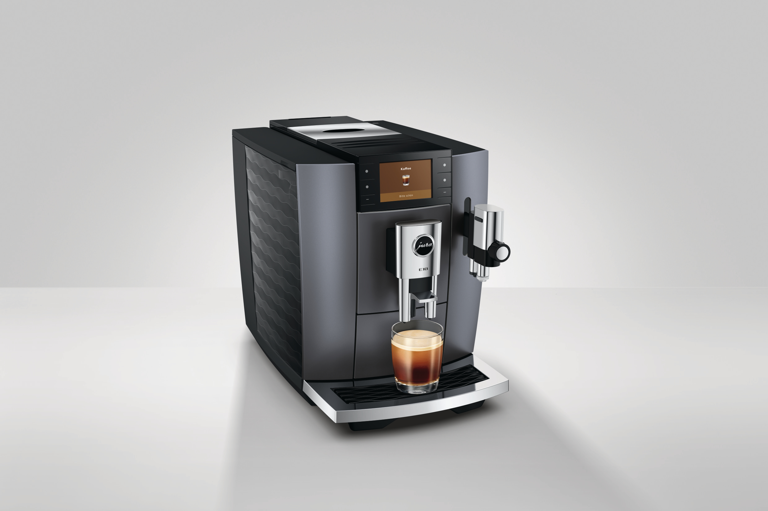 Eine schwarze Jura Kaffeemaschine mit einem Bildschirm, der „Kaffee“ und ein Kaffee-Symbol anzeigt, brüht in ein Glas.