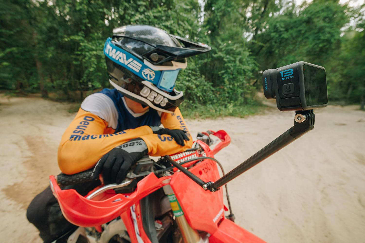 Egy motorcross versenyző teljes felszerelésben ül egy piros motorkerékpáron. Egy akciókamera van rögzítve.