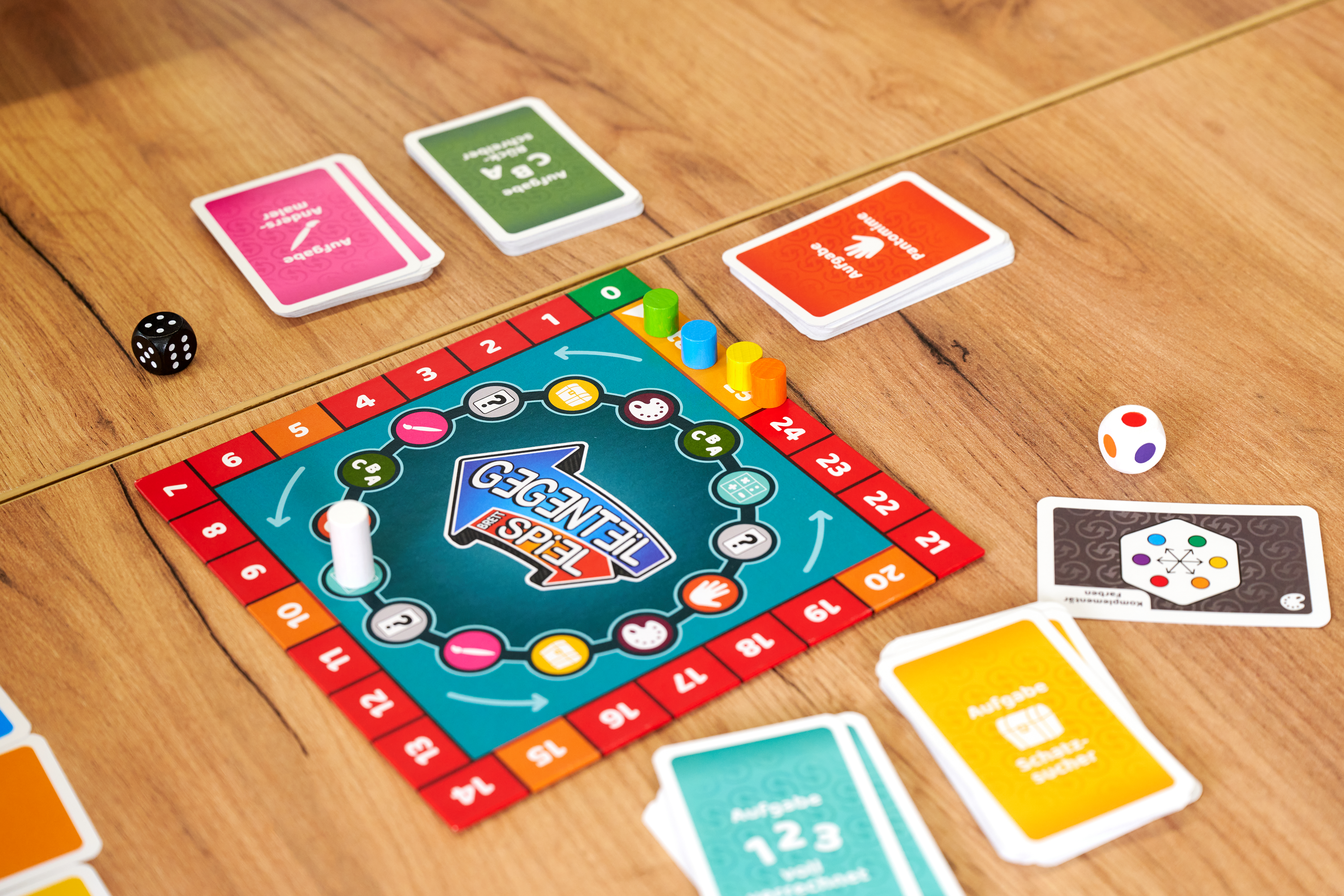 Brettspiel mit Karten, Würfeln und Spielfiguren auf Holztisch.