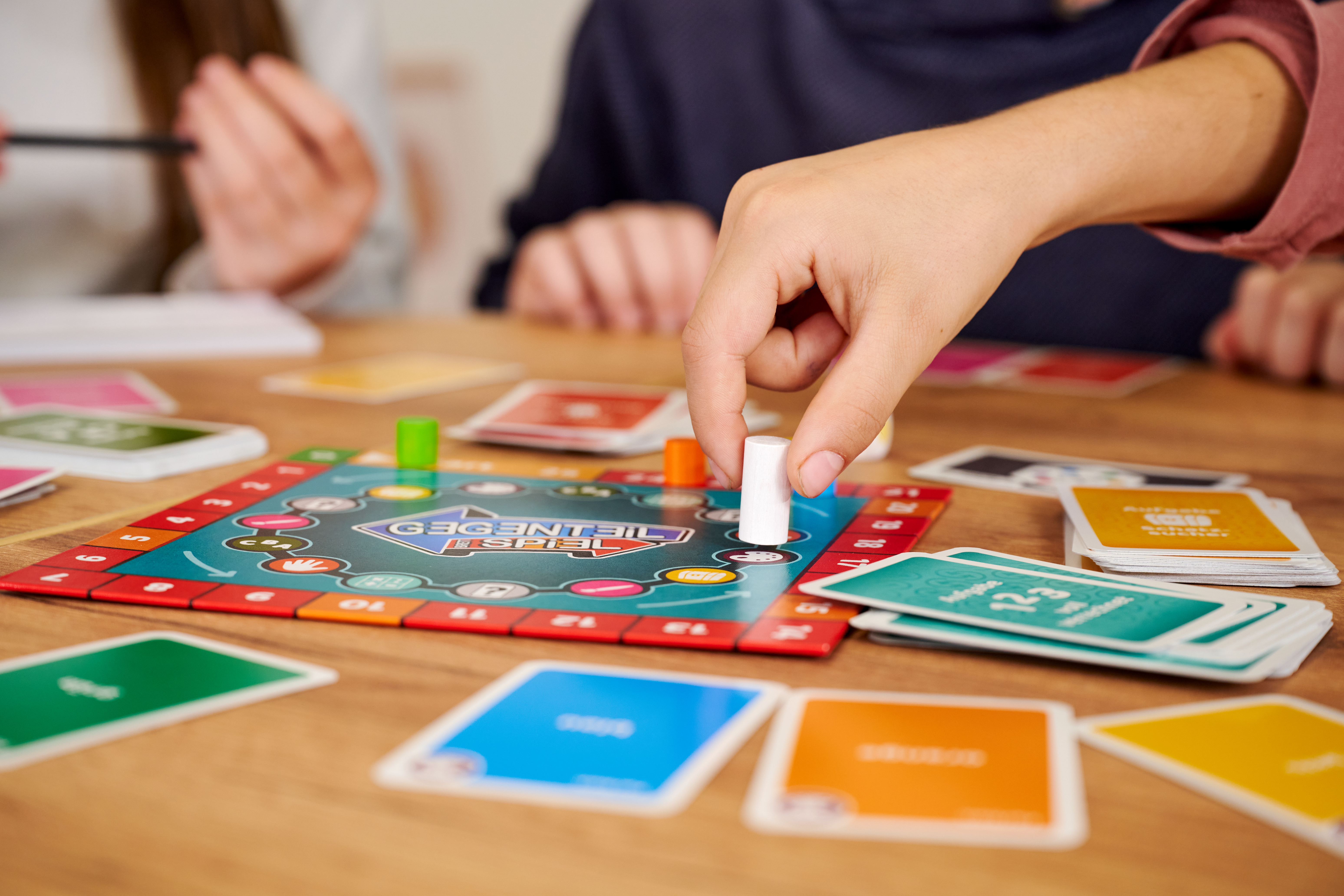 Eine Hand platziert einen weißen Spielstein auf einem Brettspiel mit Karten.
