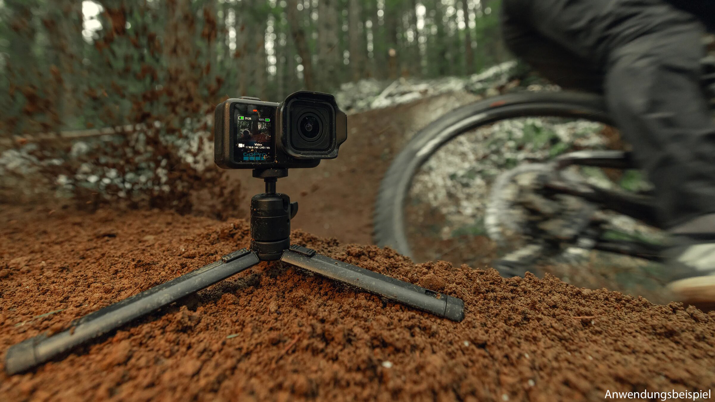 Egy állványon lévő akciókamera filmez egy mountain bike-ost az erdei ösvényen.