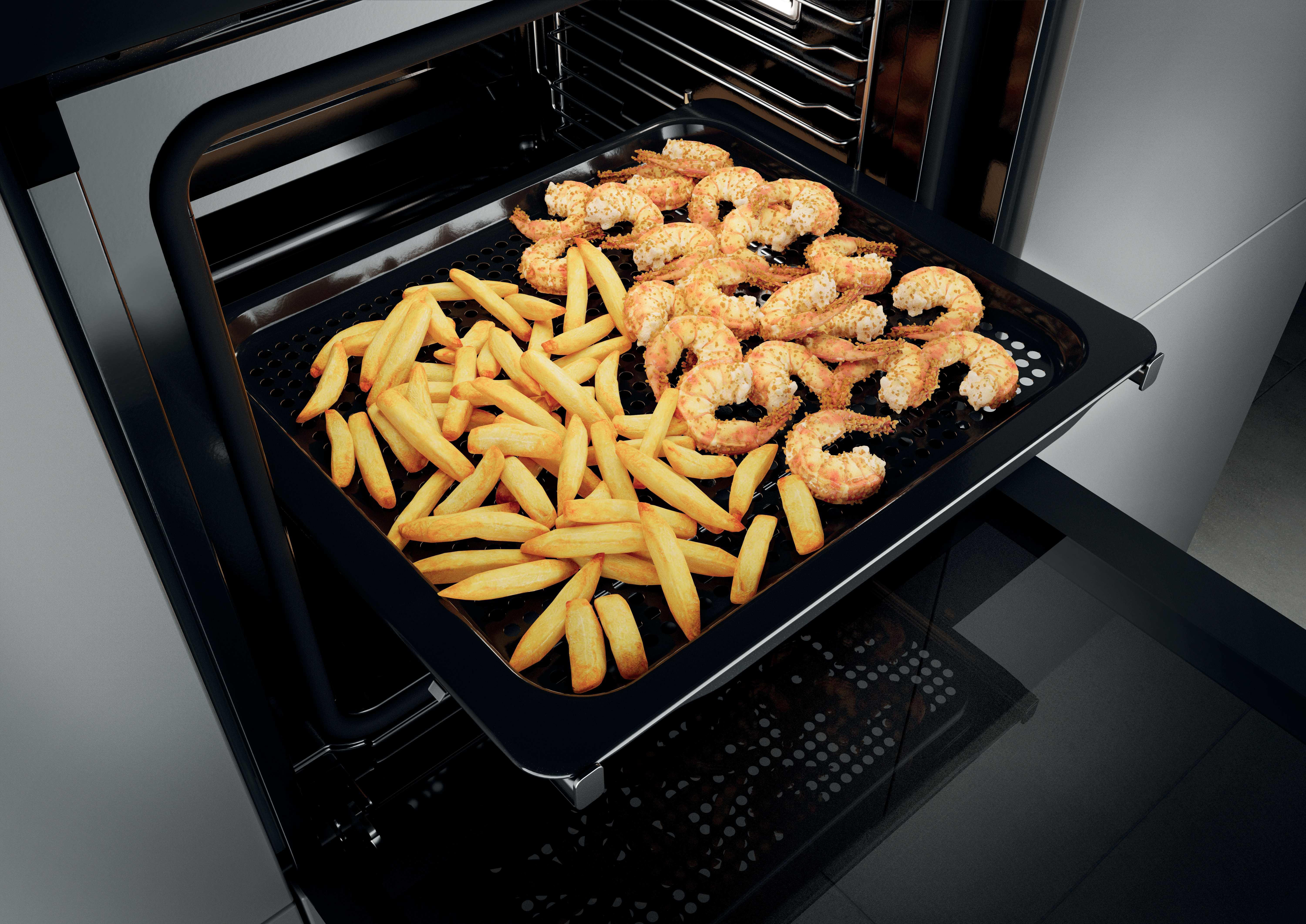Ein Backblech mit Pommes und Garnelen in einem Ofen.