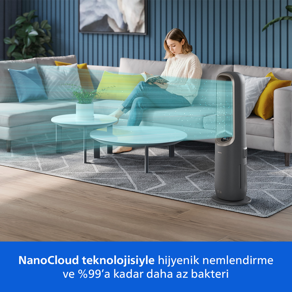 Kadın koltukta okuyor, ön planda mavi parçacıklı hava temizleyici.