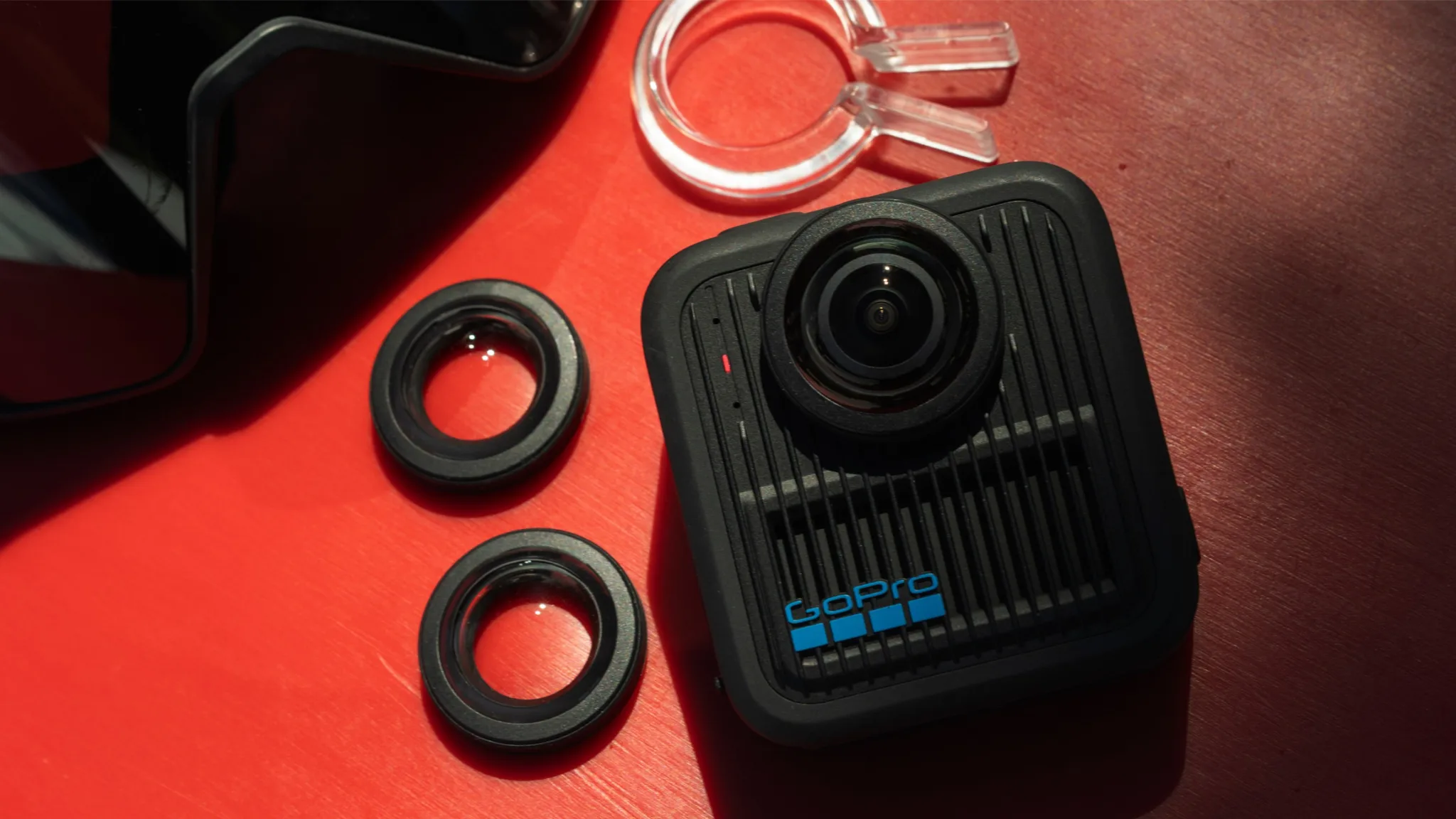 GoPro kamera tartozékokkal piros felületen.