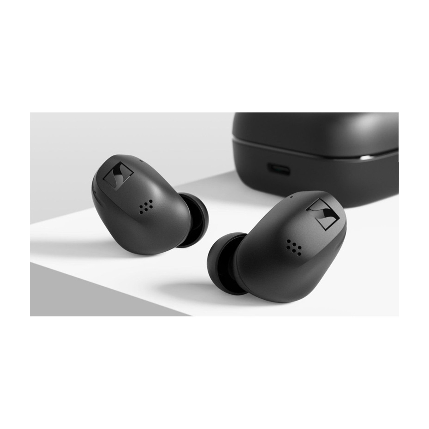 Due auricolari wireless neri e una custodia di ricarica su una superficie bianca.
