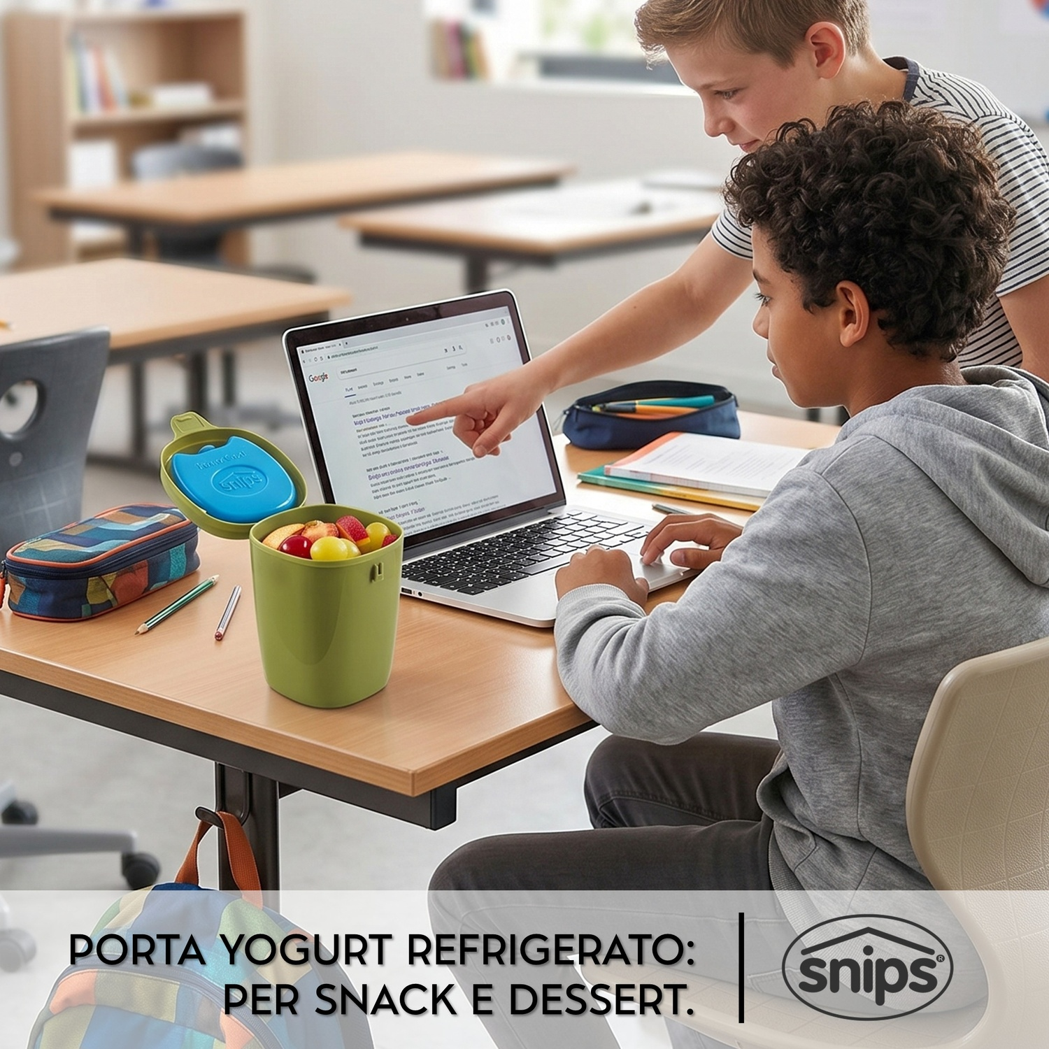 Due ragazzi studiano al computer, un contenitore verde con frutta è vicino.