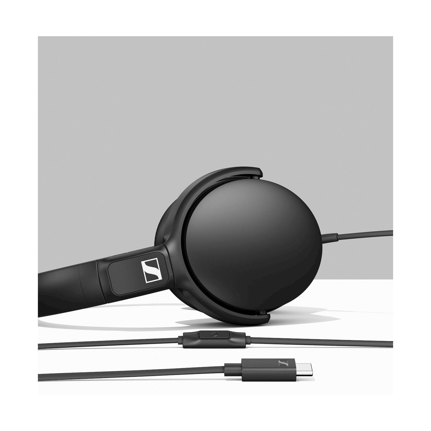 Cuffie nere con cavo e connettore USB-C su sfondo grigio.