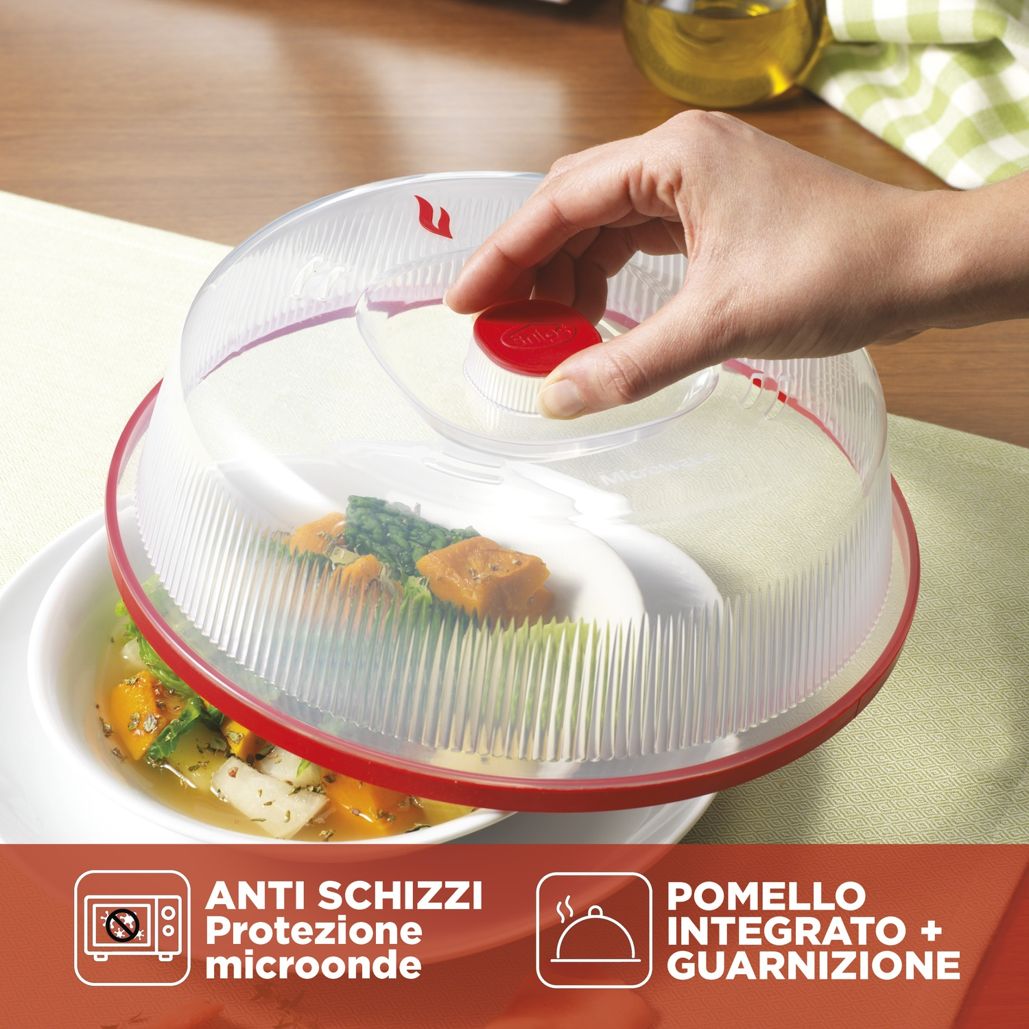 Una mano chiude una copertura trasparente per microonde con bordo rosso su un piatto di cibo.