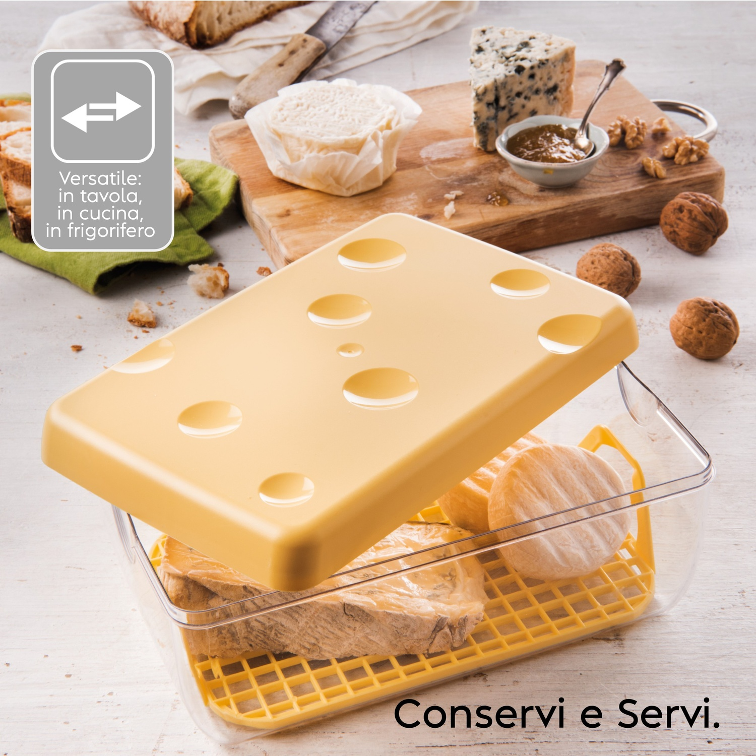 Un contenitore giallo per formaggio con fori accanto a vari formaggi e noci.