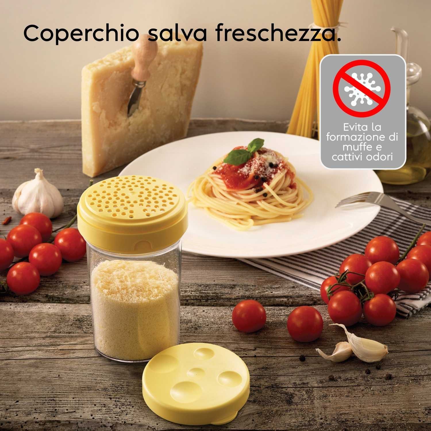 Parmigiano, spaghetti, pomodori, aglio e un contenitore giallo con formaggio grattugiato.