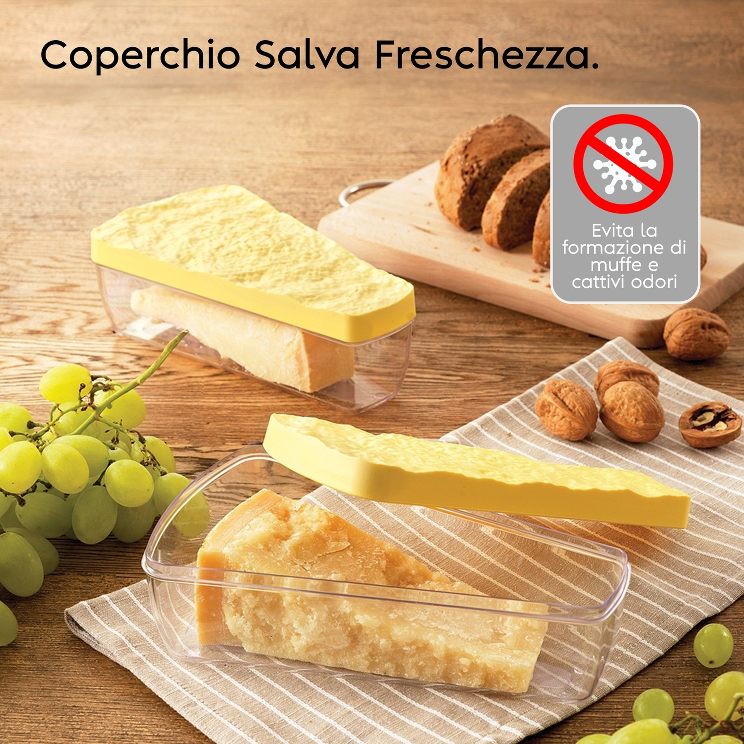 Formaggio in contenitori salva freschezza con uva e noci su tavolo legno.