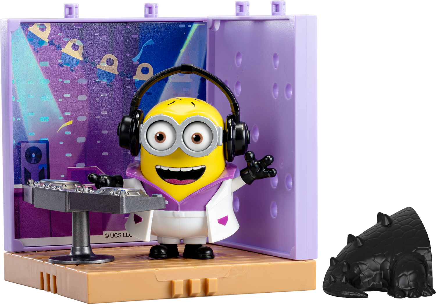 Un Minion amarillo con auriculares pincha música junto a un juguete de dinosaurio negro.