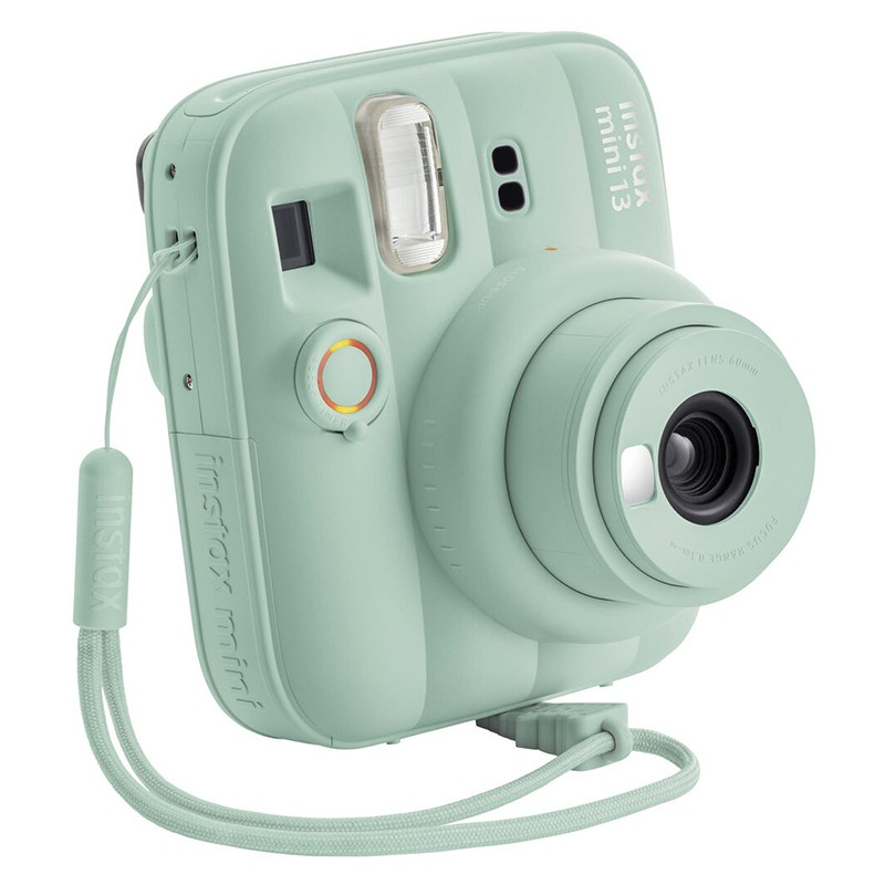 Una cámara instantánea Instax Mini 13 verde menta con correa de muñeca. Fondo blanco.