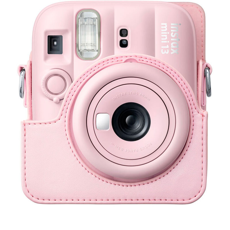 Una cámara Instax Mini 13 rosa en funda protectora, mostrando el objetivo.