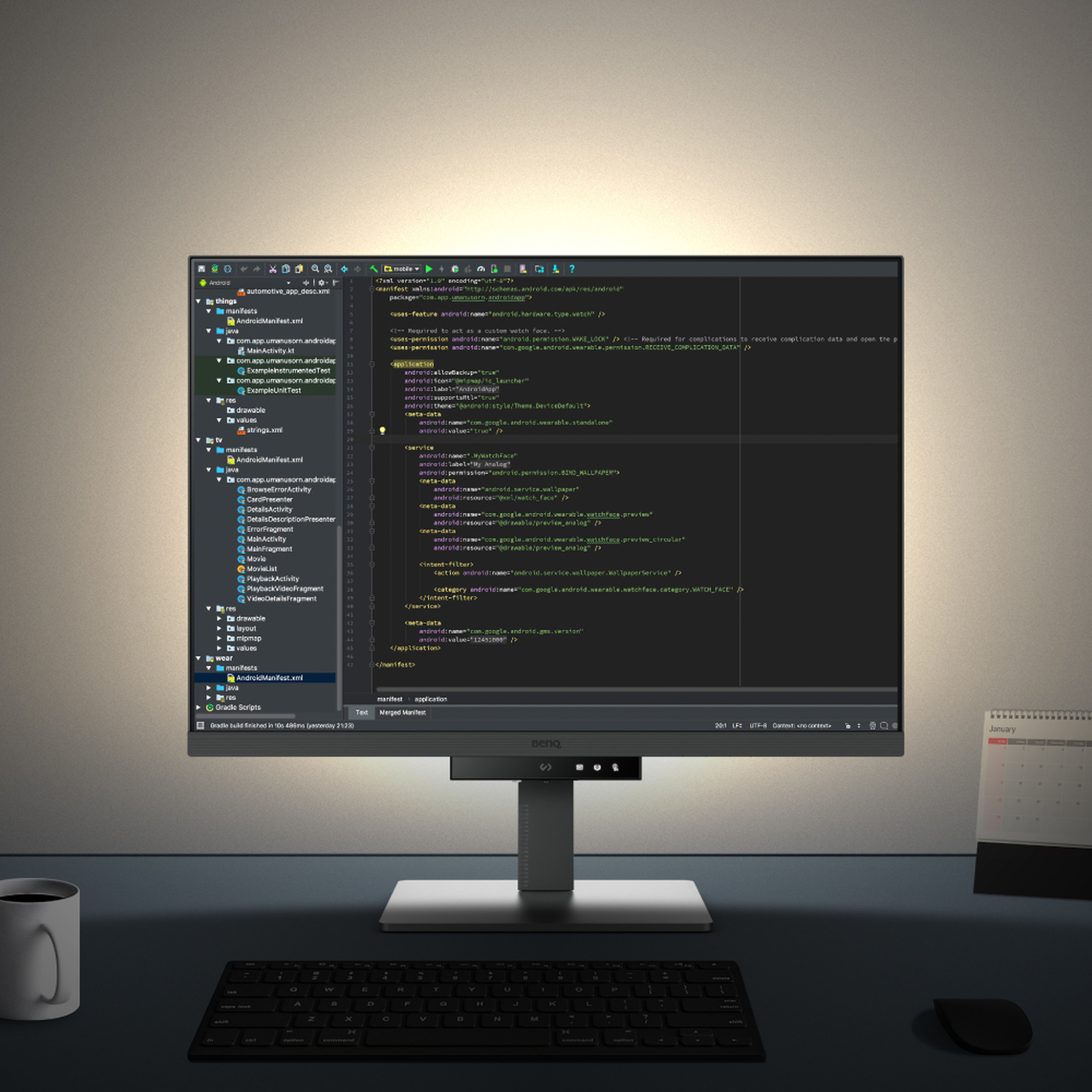 Una scrivania scura con uno schermo del computer che mostra codice, tastiera e tazza.