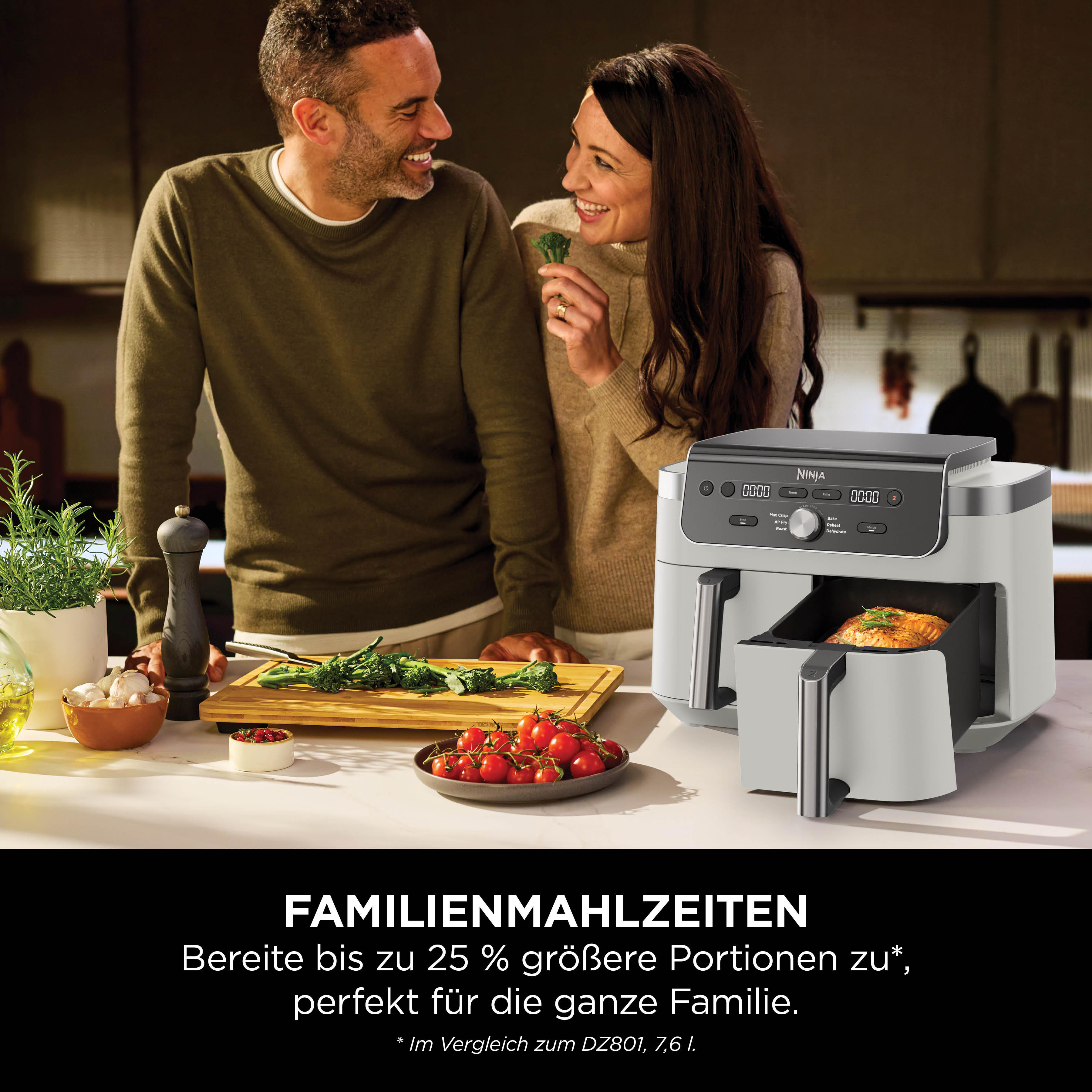 Ein Paar lacht und bereitet Essen zu, während ein Ninja Air Fryer daneben steht.