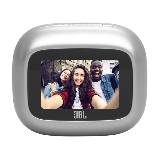 Trzech radosnych przyjaciół robi sobie selfie przed ceglanym murem. Na urządzeniu widnieje logo JBL.