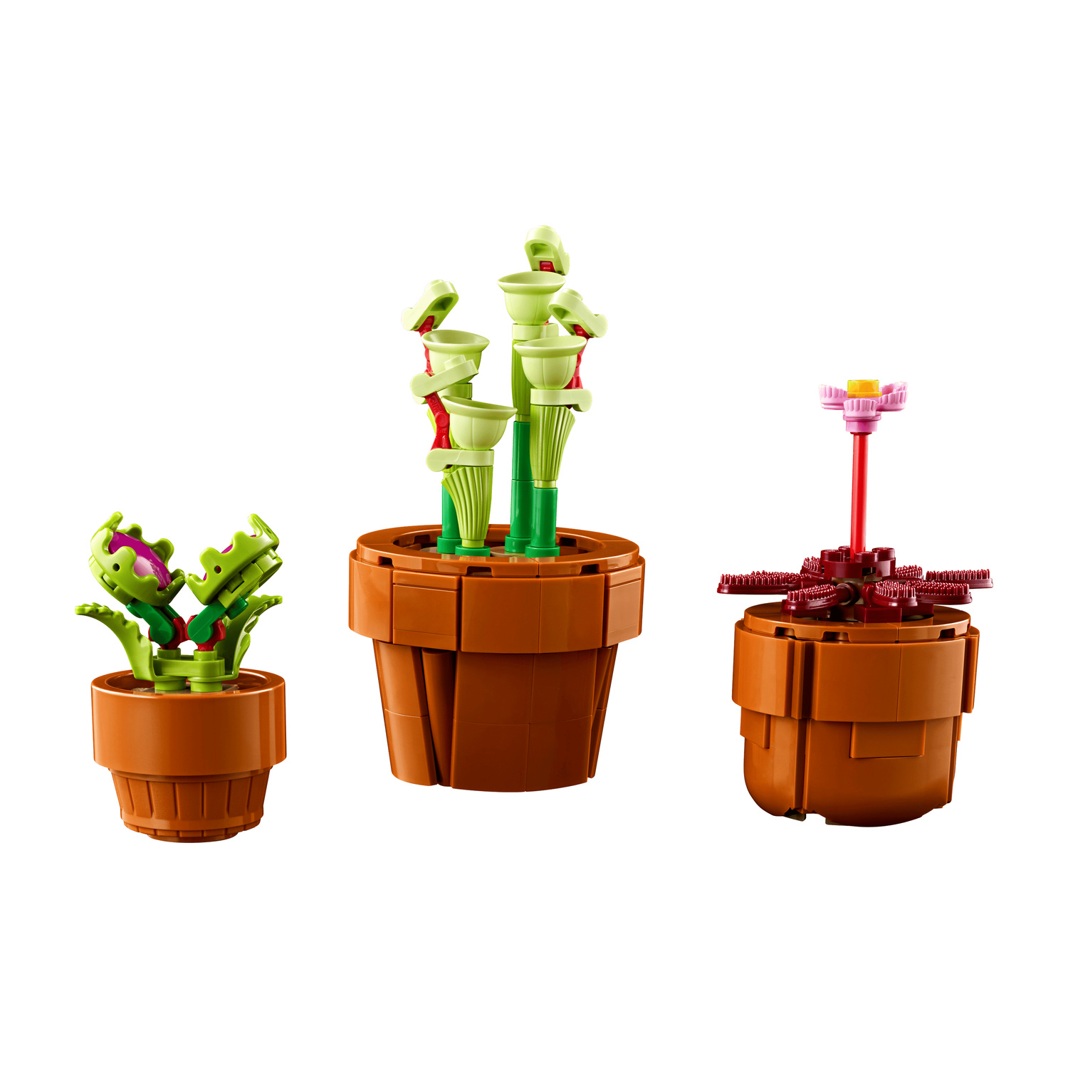 Tre piante Lego in vasi marroni: una carnivora, piante con coppe verdi e una con fiore rosa.