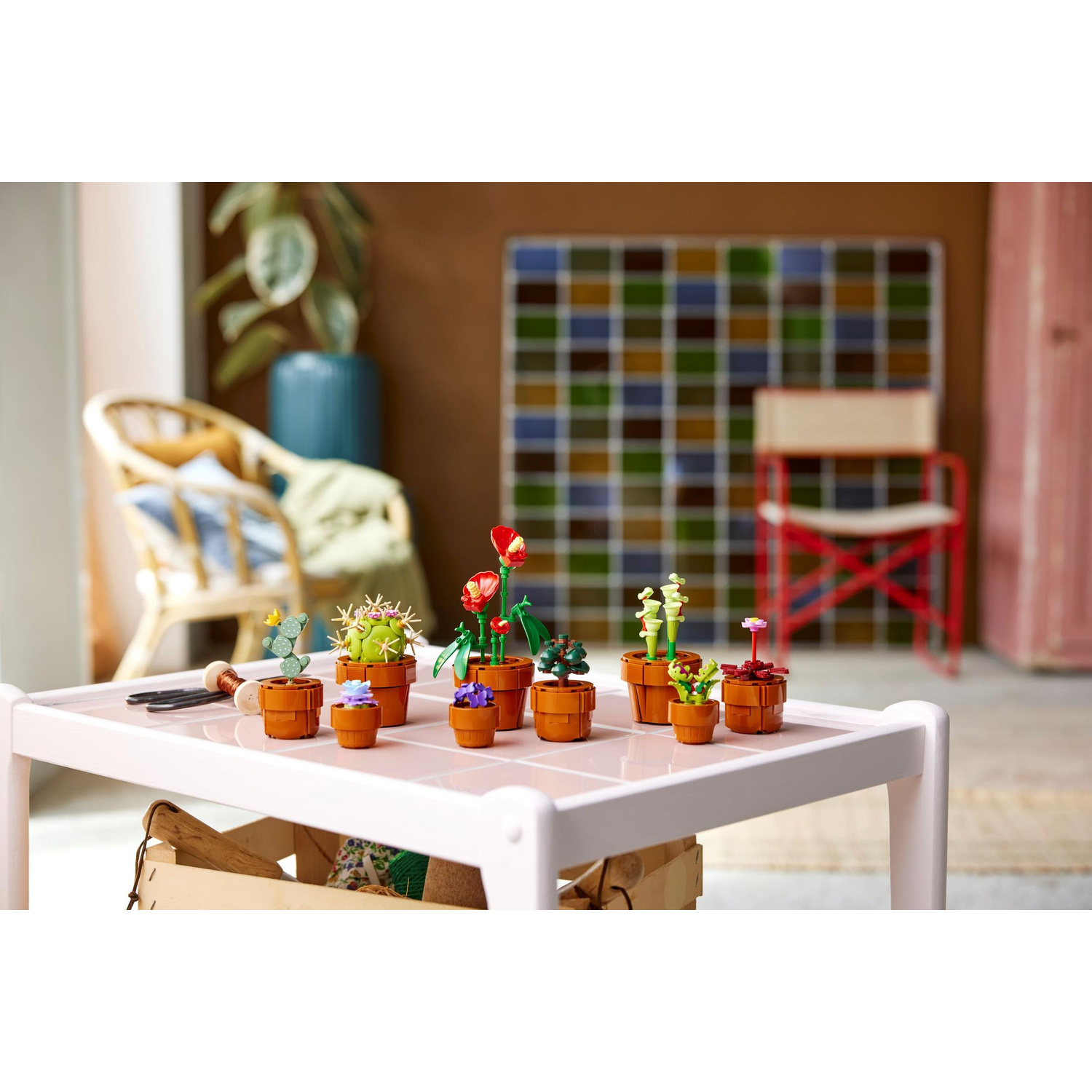 Diverse piante in vaso e cactus Lego esposti su un tavolo.