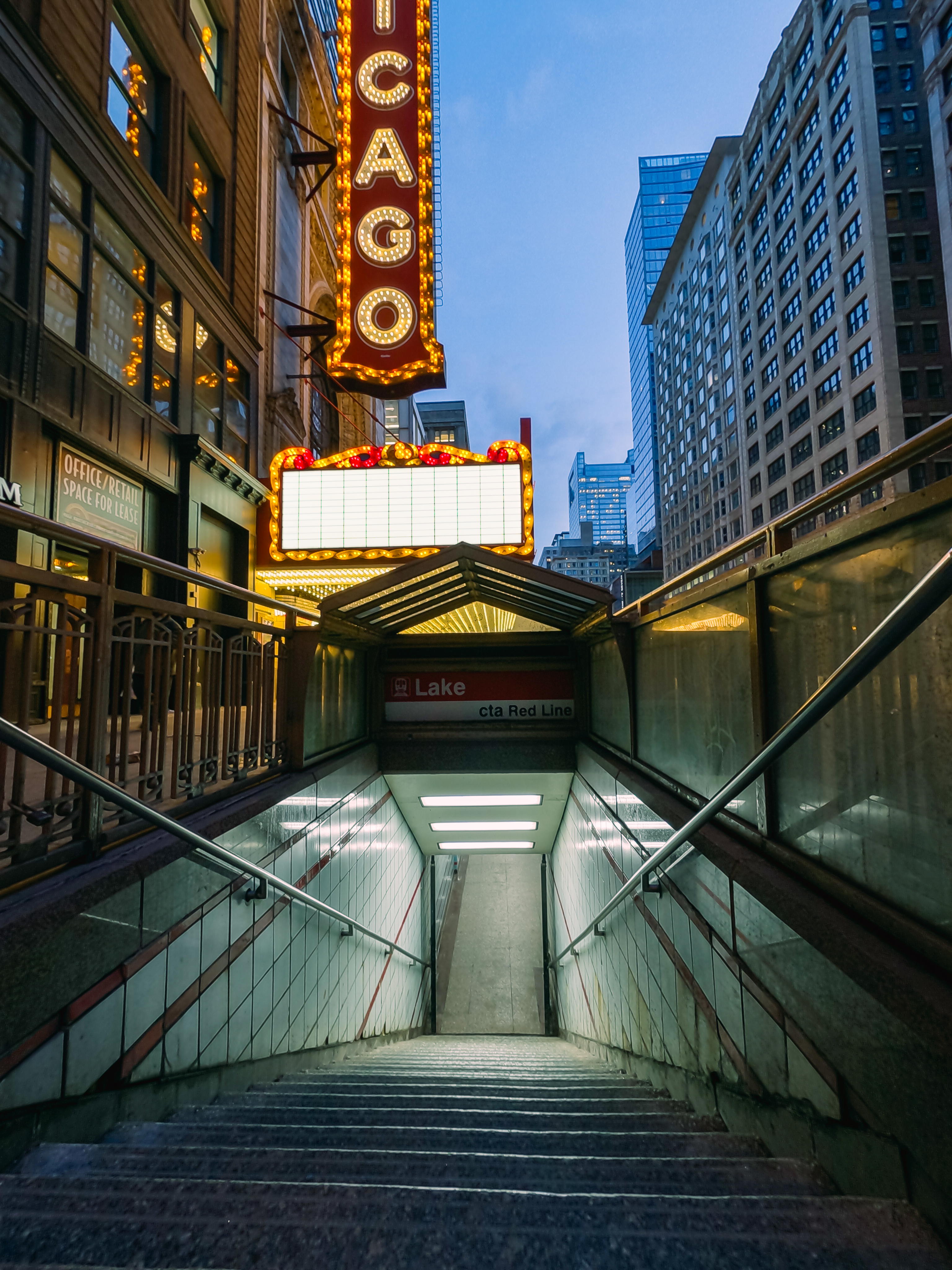 Chicago-Theaterschild über U-Bahn-Treppen in der Dämmerung. Gebäude und Himmel sichtbar.