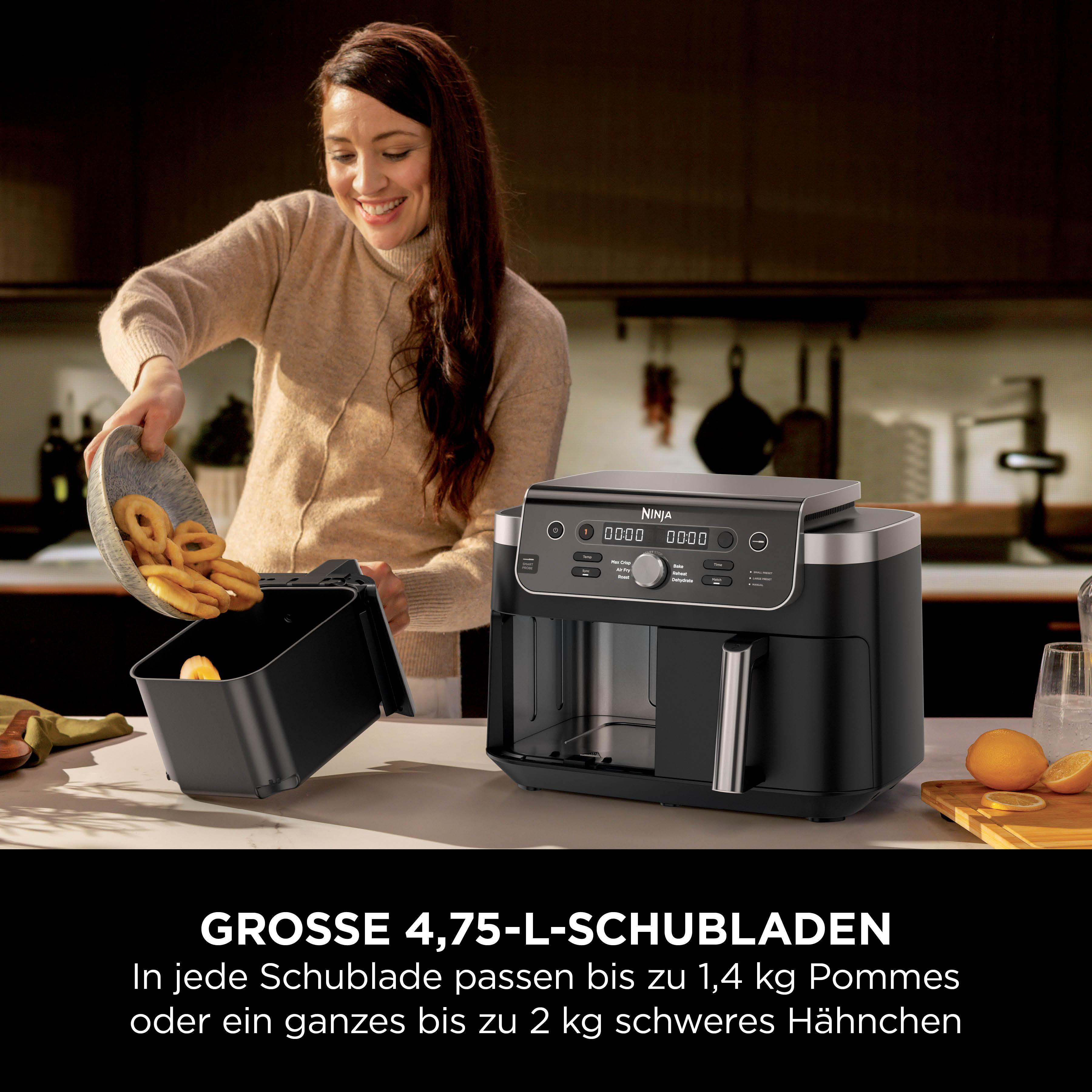 Eine Frau gibt Pommes Frites in eine schwarze Heißluftfritteuse. daneben liegen Orangen.