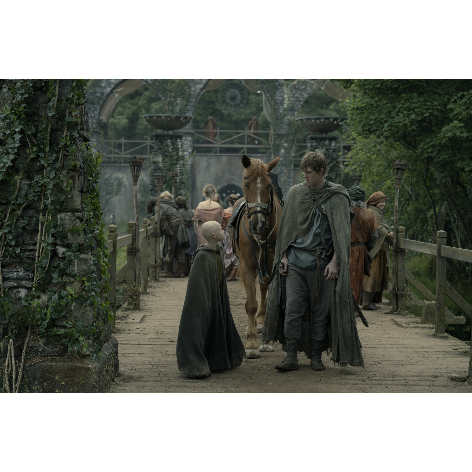 Un homme avec un cheval et un garçon chauve sur un pont avec des gens.